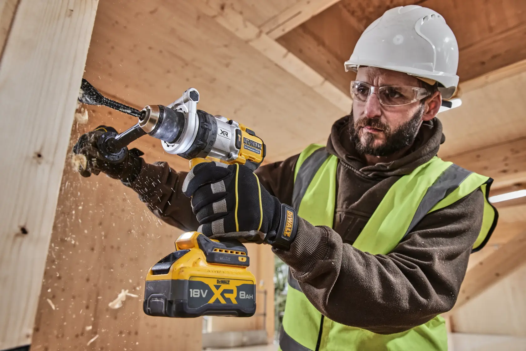 Person drilling wood with DEWALT XR 18V 8Ah cordless drill in a construction setting, wearing safety gear.