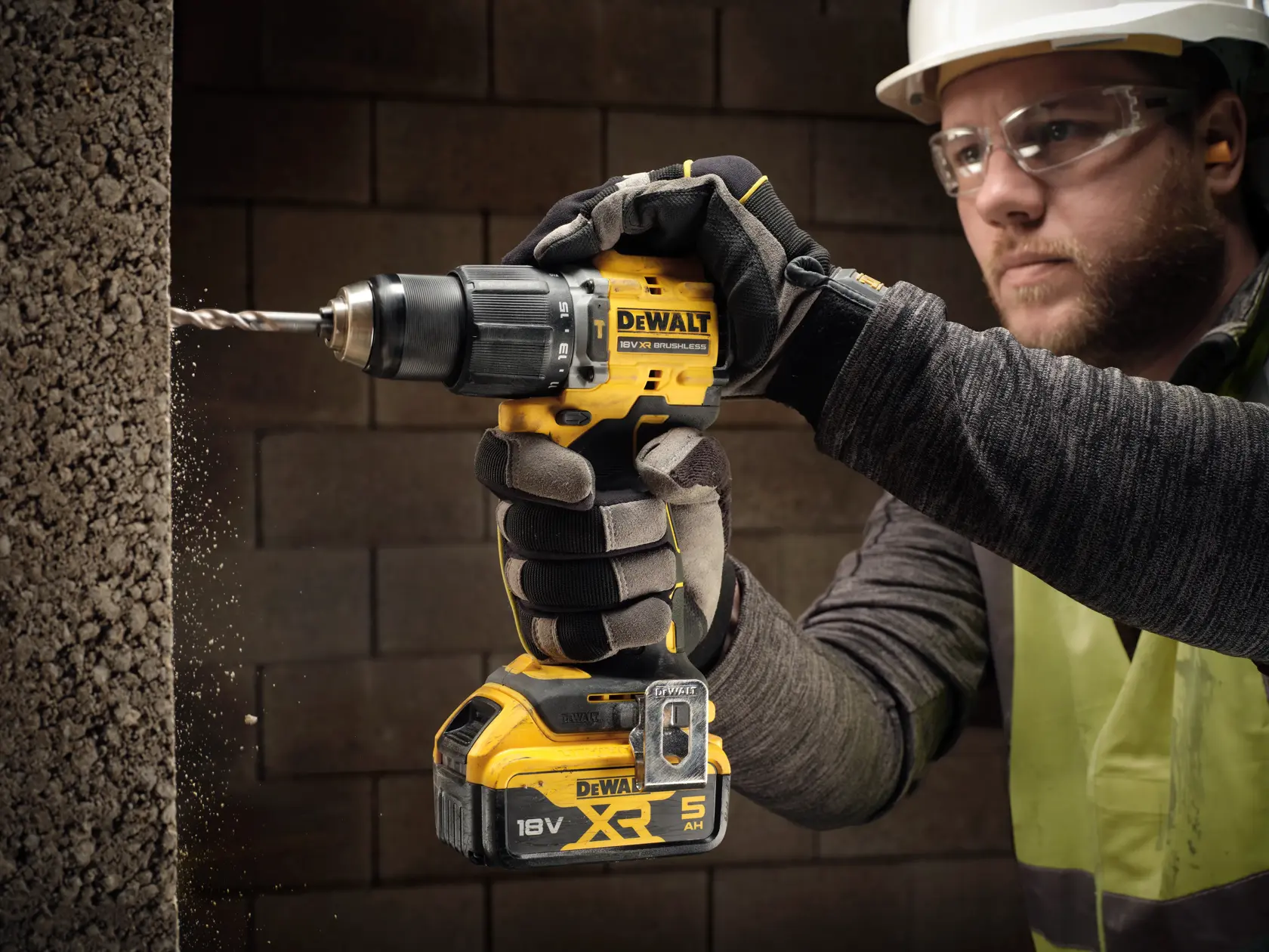 DEWALT cordless drill in use drilling into concrete, worker wearing gloves and safety gear.