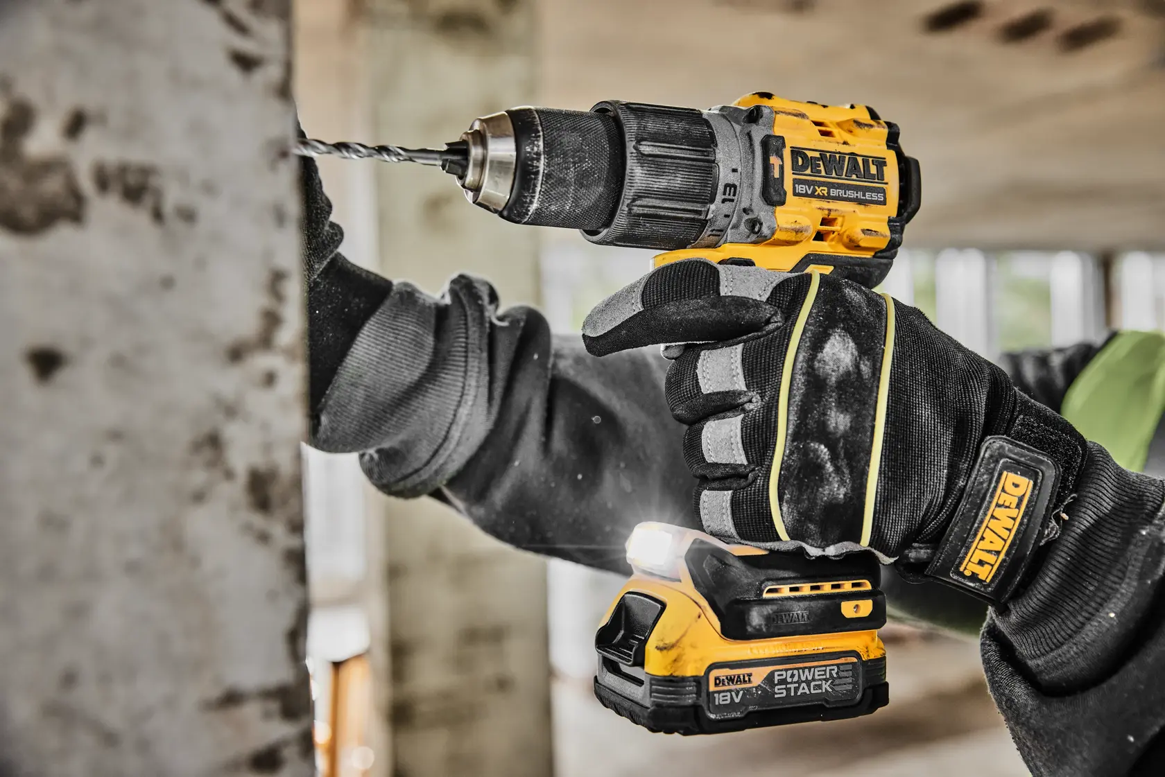 A close-up view of a person using a yellow and black DEWALT cordless drill to make a hole in a metal surface. The person is