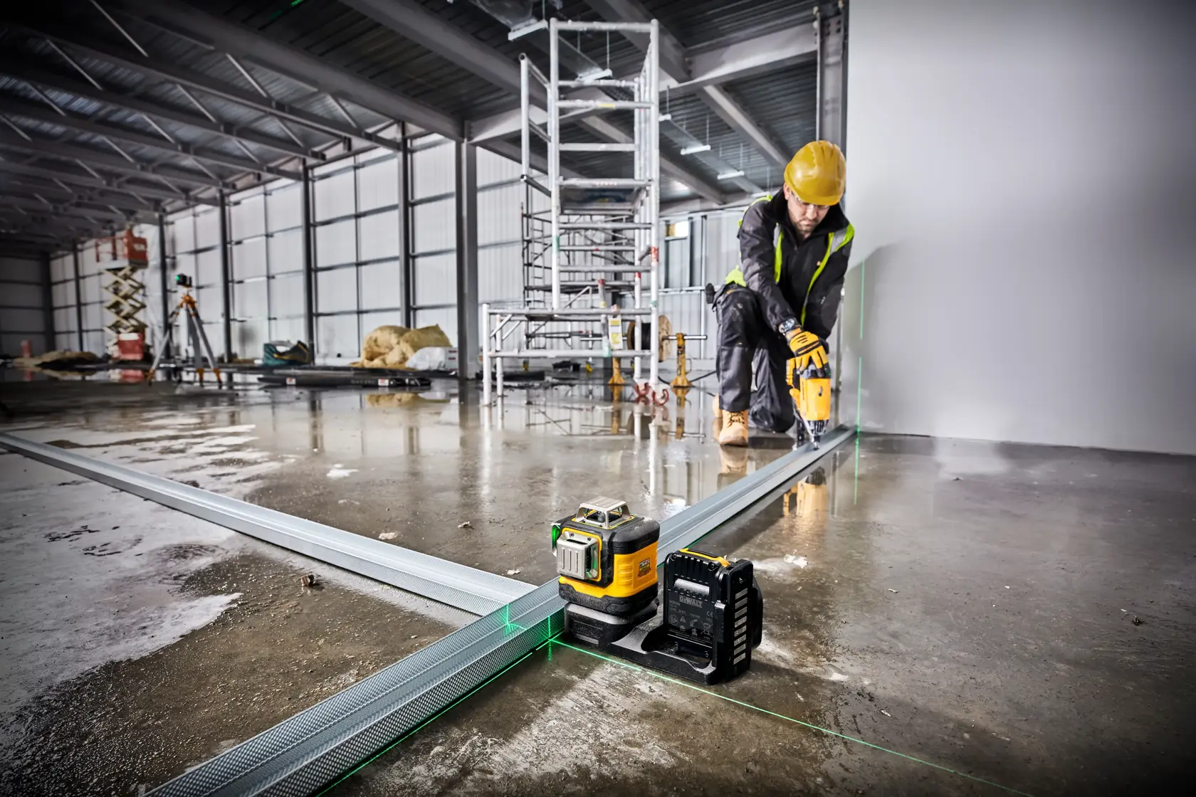 DEWALT green laser tool in use on a construction site for precise alignment of metal tracks.