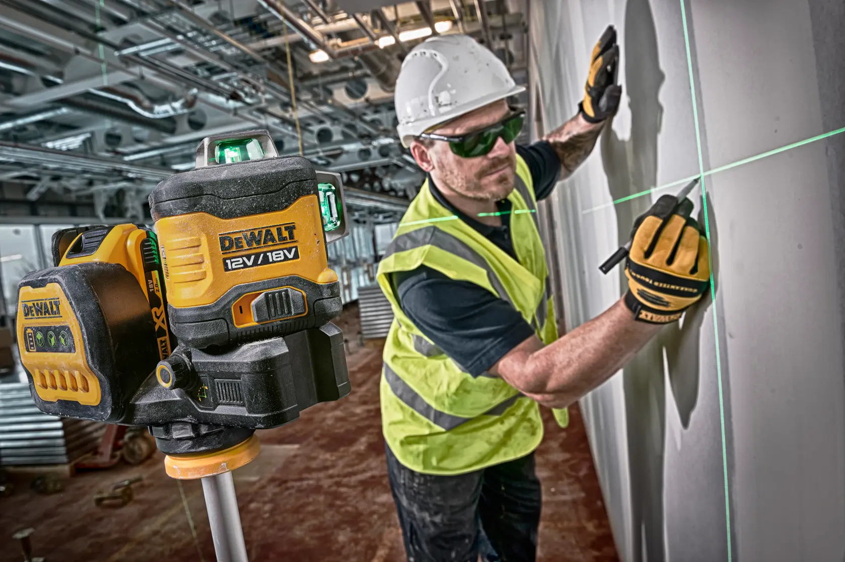 DEWALT laser level used by a worker in a vest and helmet marking lines on a wall at a construction site.