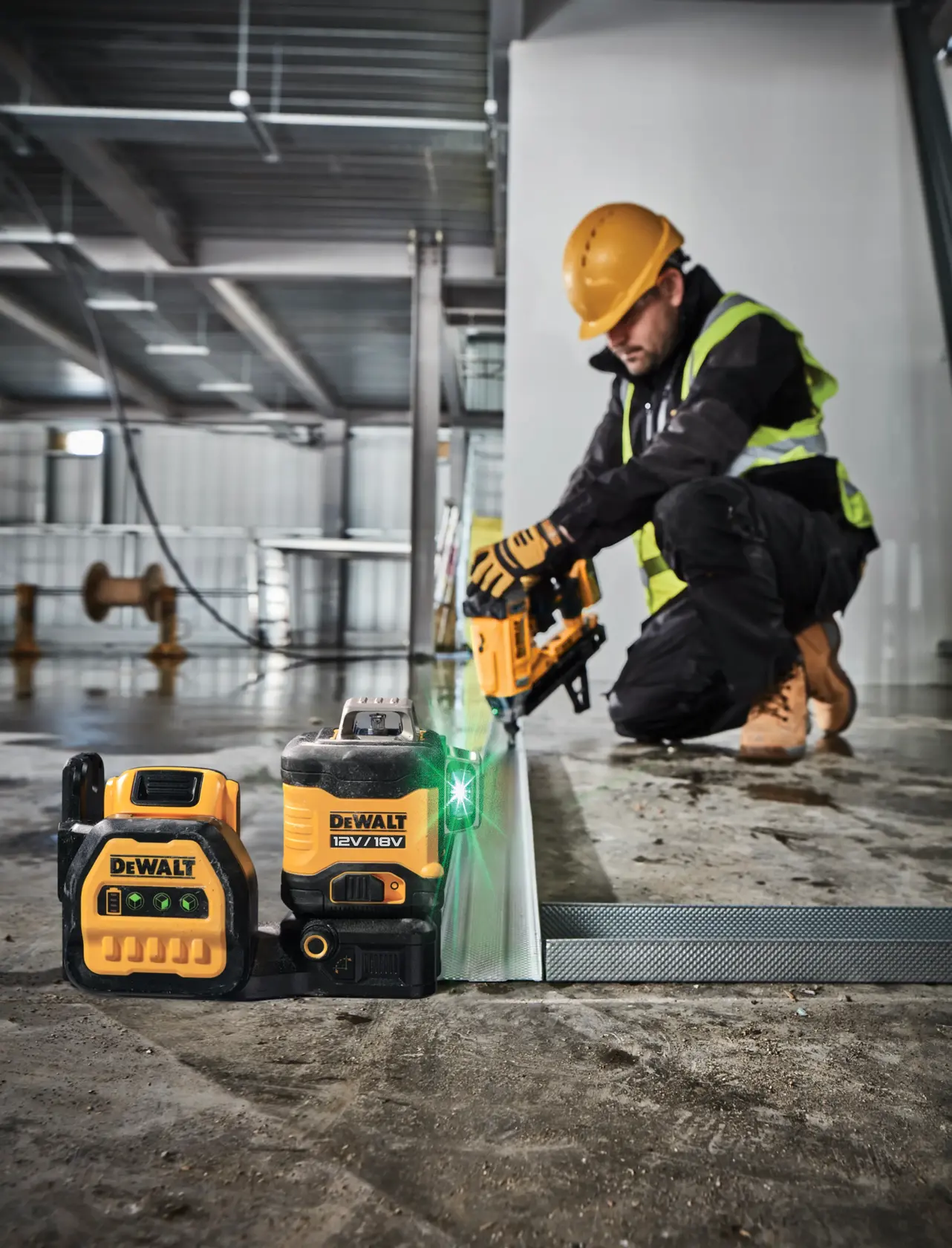 DEWALT DCE089NG18 laser level and tool on a construction site with a worker installing metal framing.