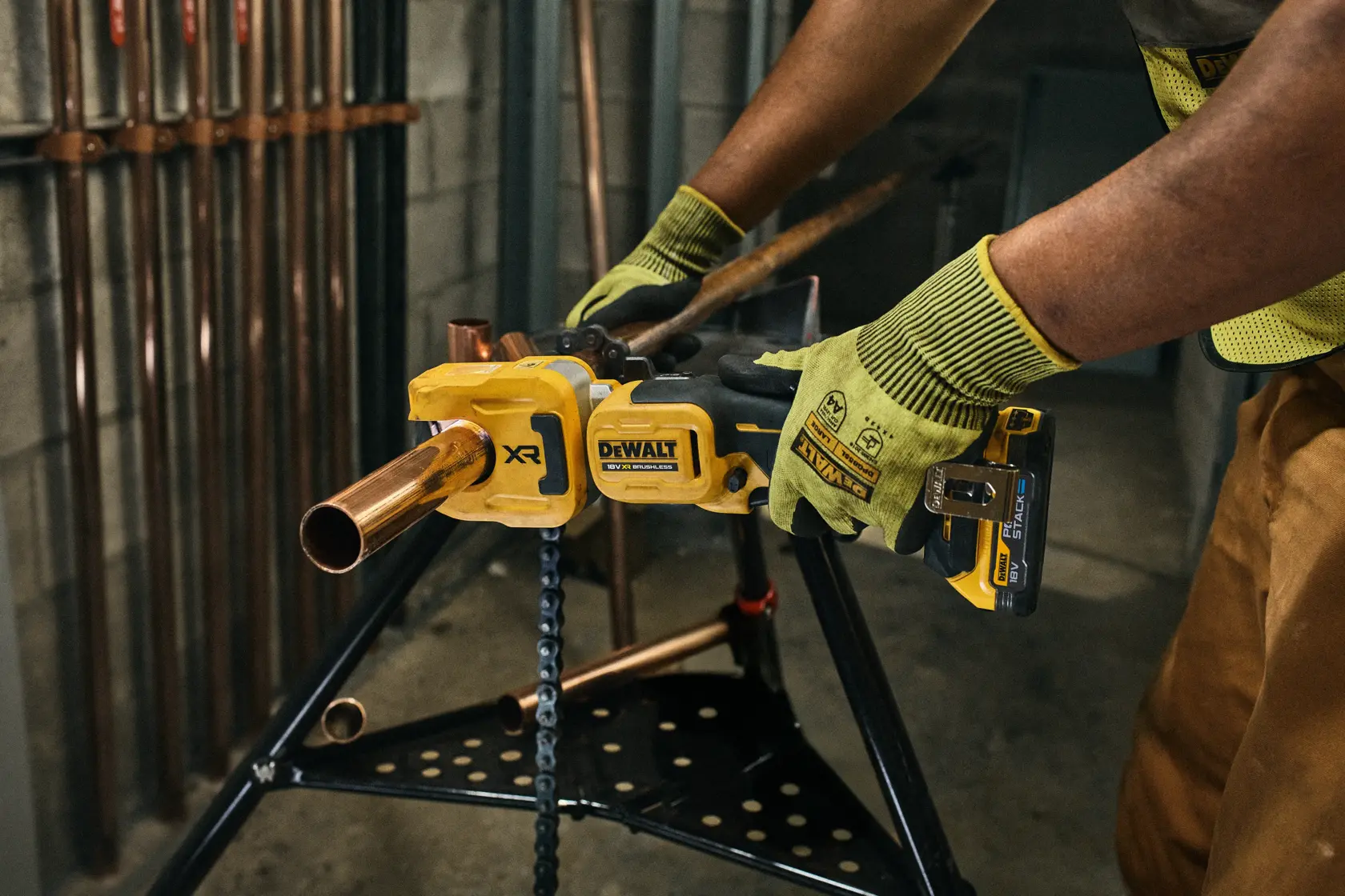 DEWALT pipe tool in use. Photography category. SKUs: DCE154N, DCE154N-XJ. Worker wears gloves.