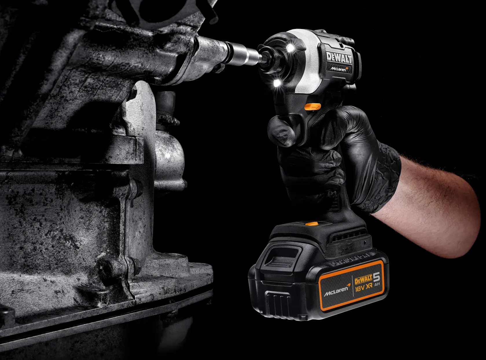 DEWALT cordless impact driver being used on metal machinery by a gloved hand, close-up view.