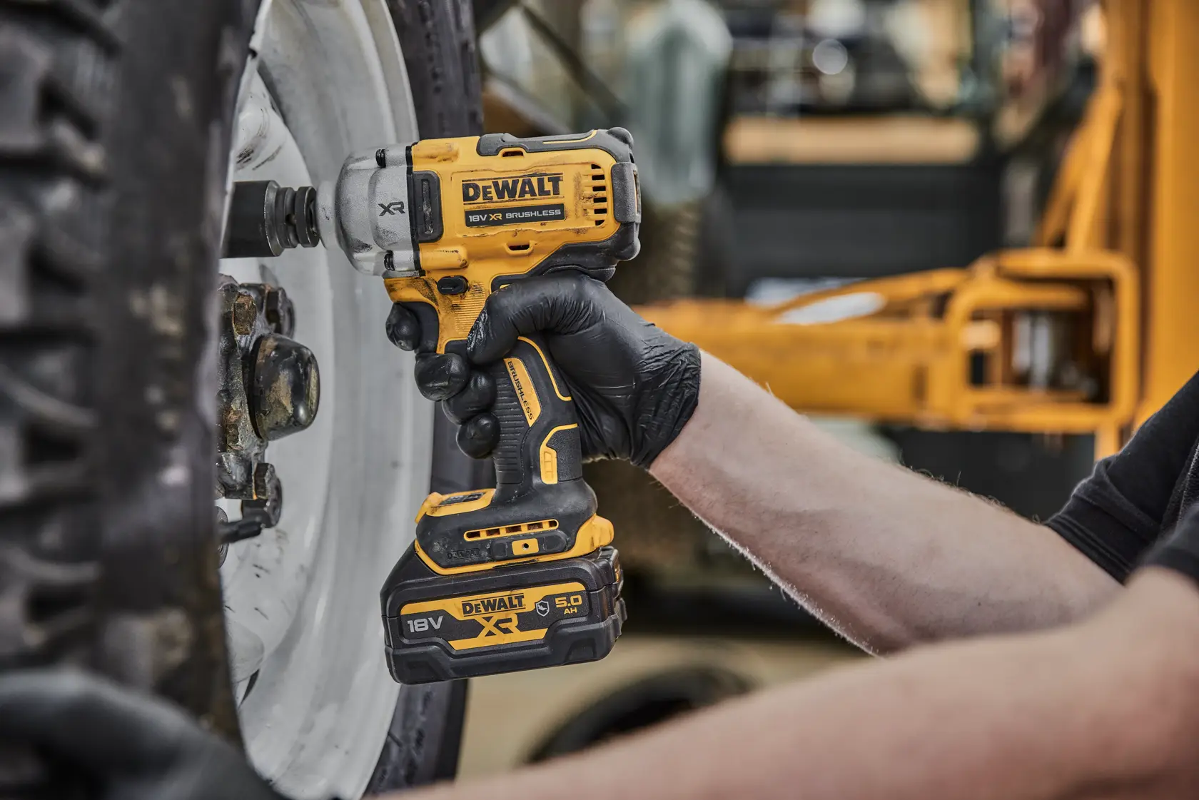 DEWALT cordless impact wrench used to loosen lug nuts on a vehicle wheel.