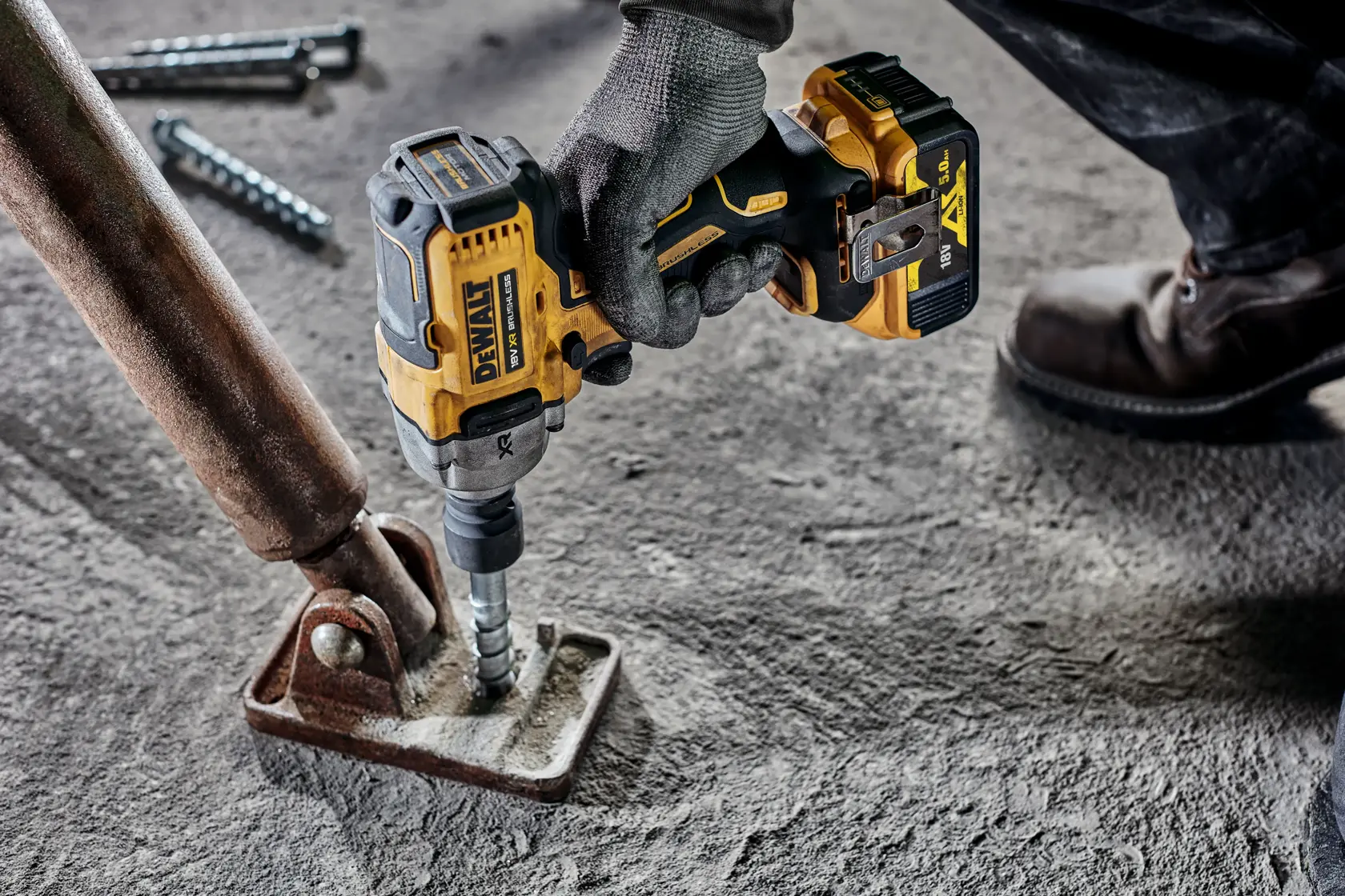 DEWALT cordless impact wrench being used to fasten metal to concrete in an industrial setting.