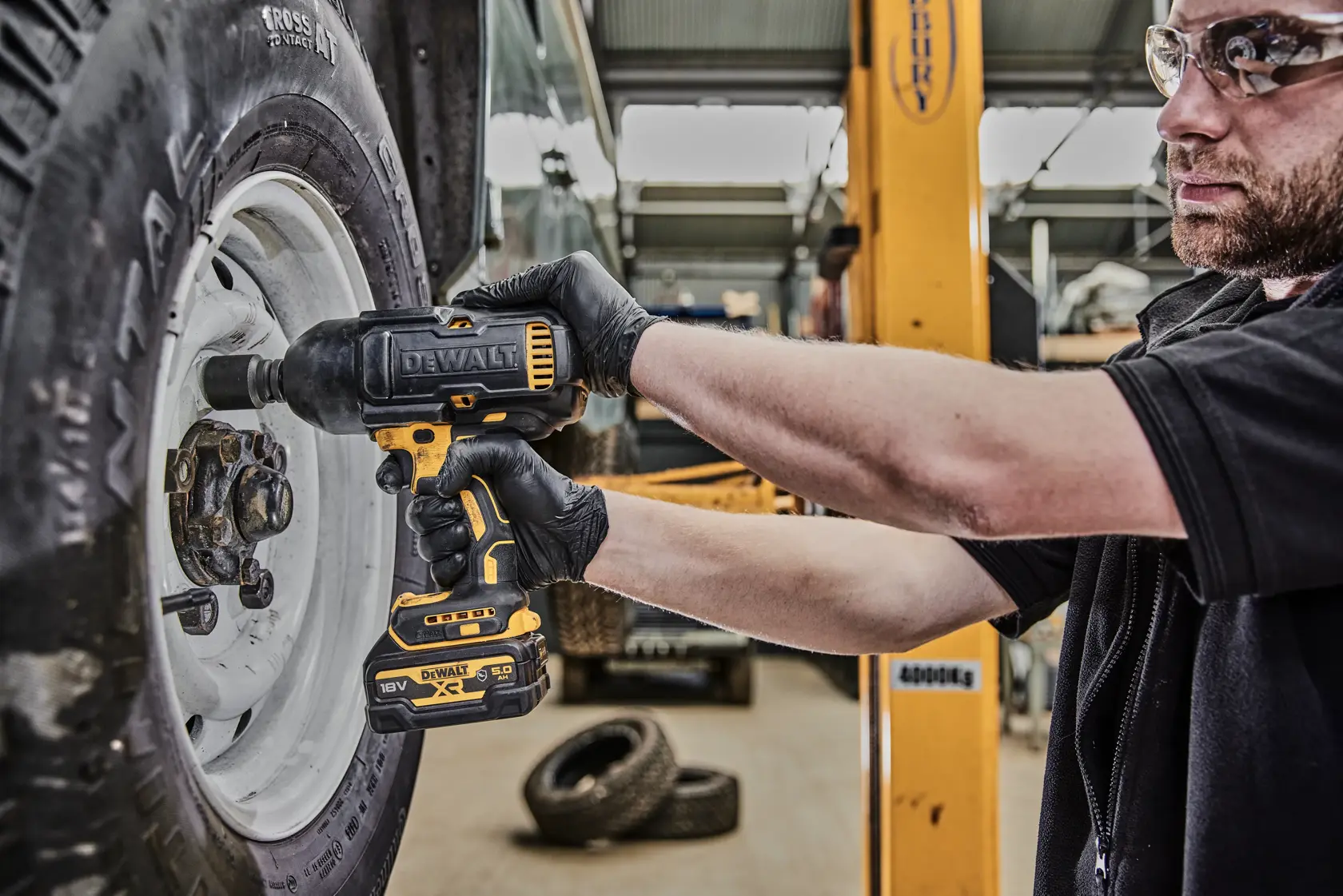 DEWALT impact wrench DCF900P2G used to tighten a wheel lug nut in an automotive workshop.