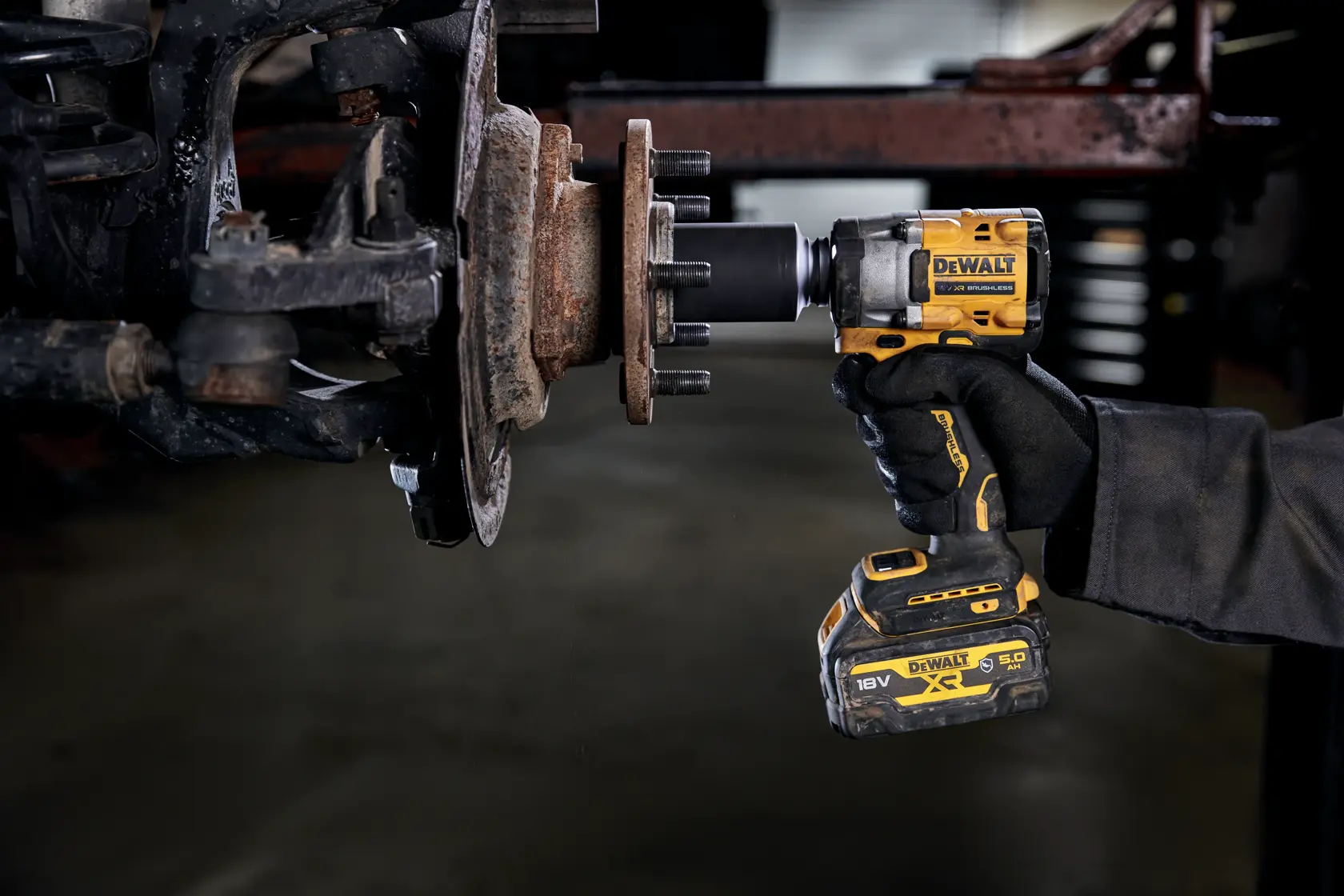 A person using a DEWALT cordless impact wrench (model DCF921P2G) to remove or tighten lug nuts on a vehicle wheel hub.