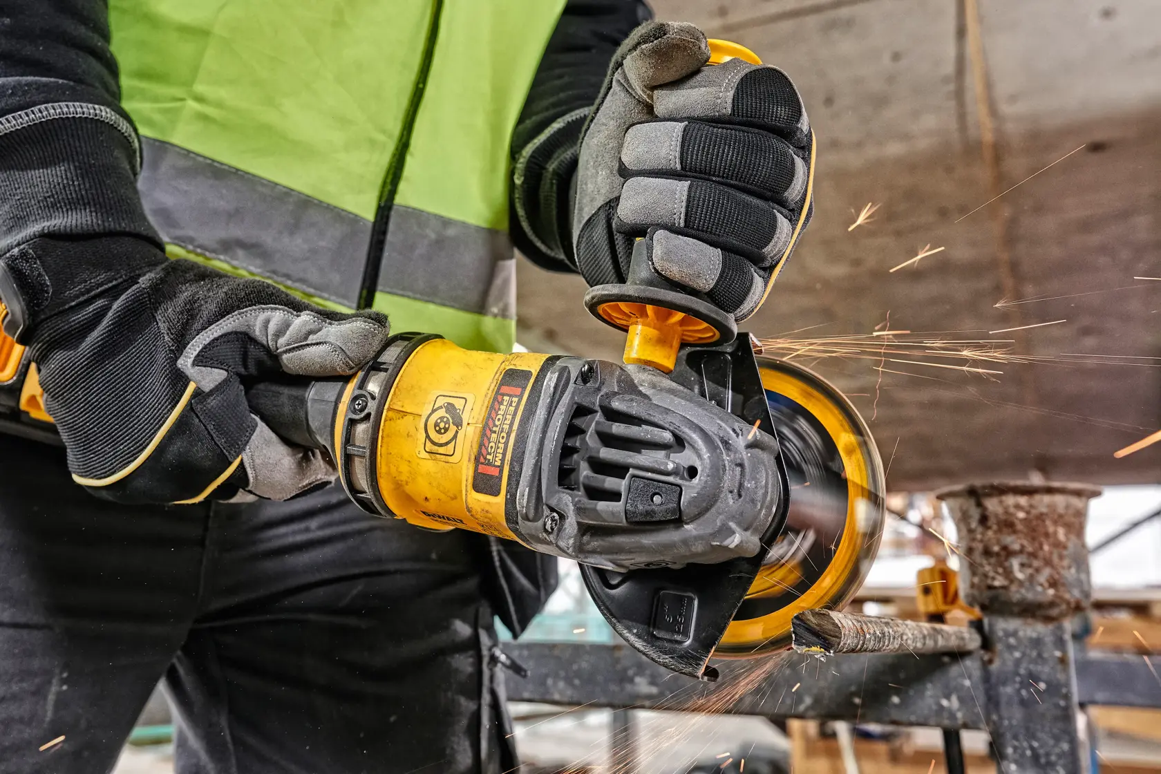 Worker uses a DEWALT angle grinder with sparks flying during metal cutting at a construction site.