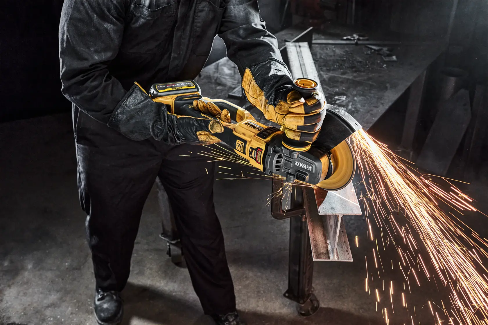 Person using a DEWALT angle grinder, producing sparks while cutting metal in an industrial workshop.