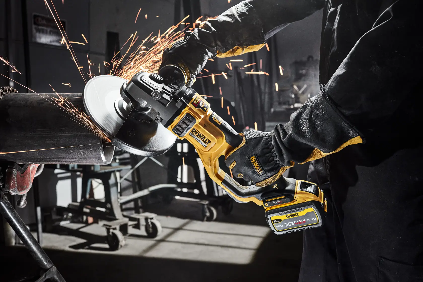 Person using a DEWALT cordless grinder, cutting metal pipe with sparks flying in a workshop.
