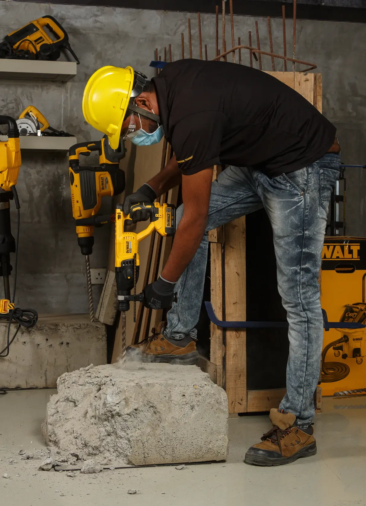 Worker uses a DEWALT DCH133NT rotary hammer drill on concrete, wearing safety gear in a construction setting.