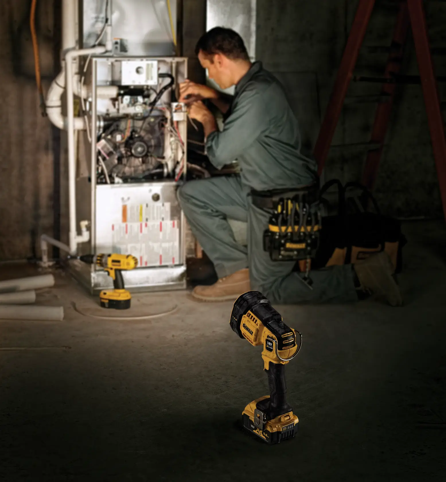 A DEWALT DCL043 cordless handheld spotlight is placed on the floor in the foreground, while a worker in coveralls is servicing an electrical unit in a dimly lit industrial setting.