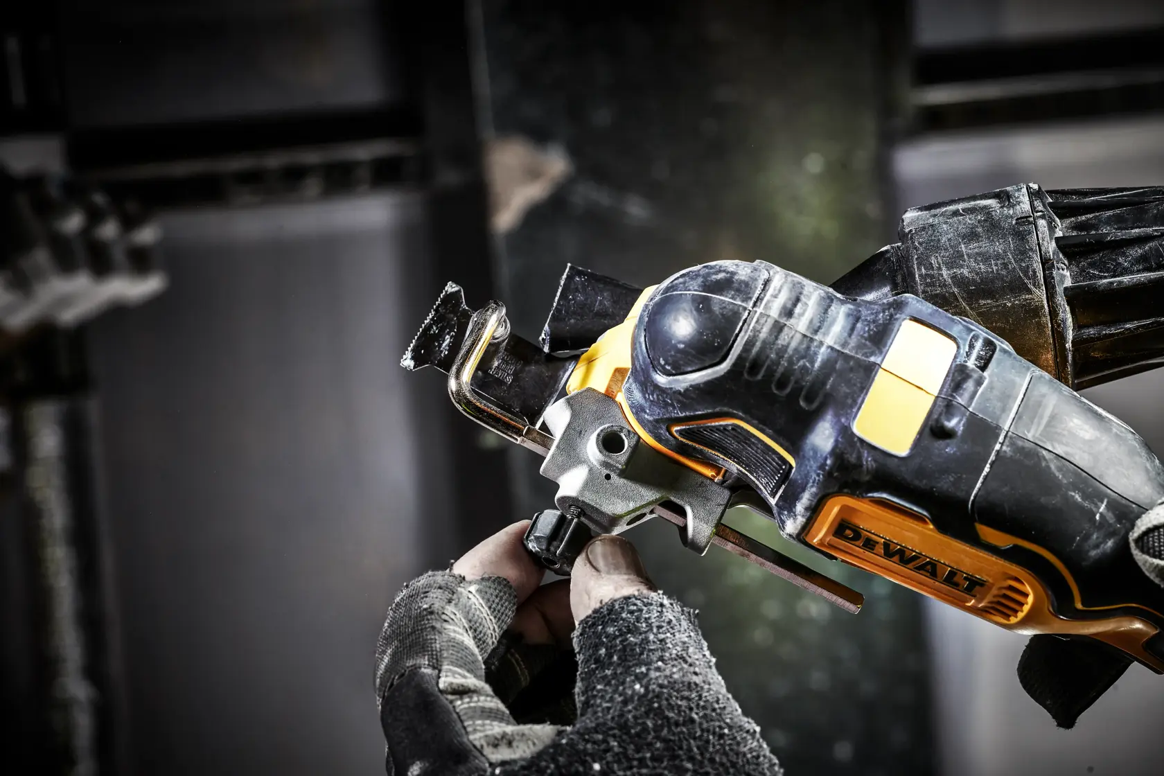 Gloved hand adjusts a DEWALT cordless oscillating multi-tool in an industrial workshop setting.