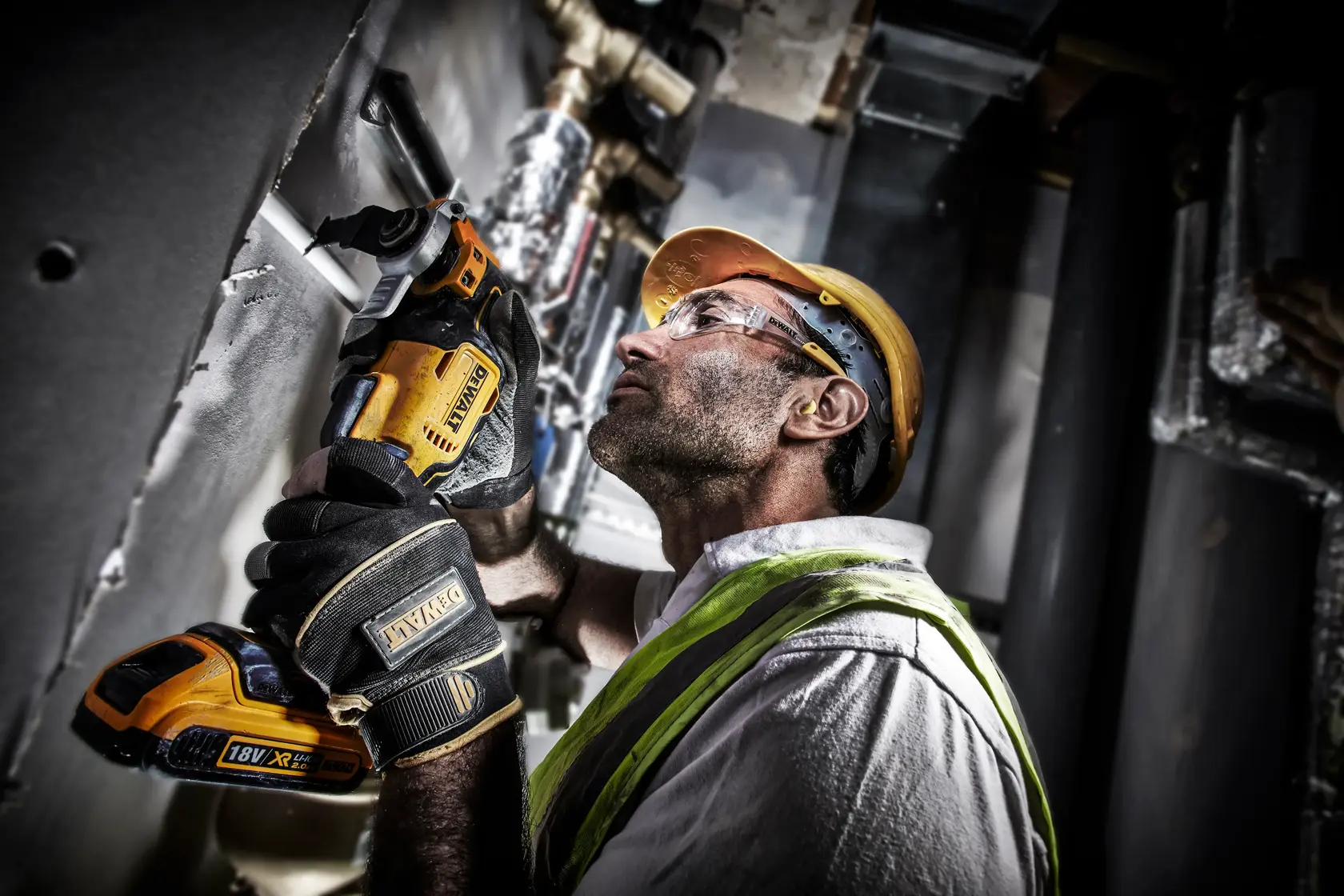 Person uses a DEWALT cordless multi-tool to cut wall material on a construction site.