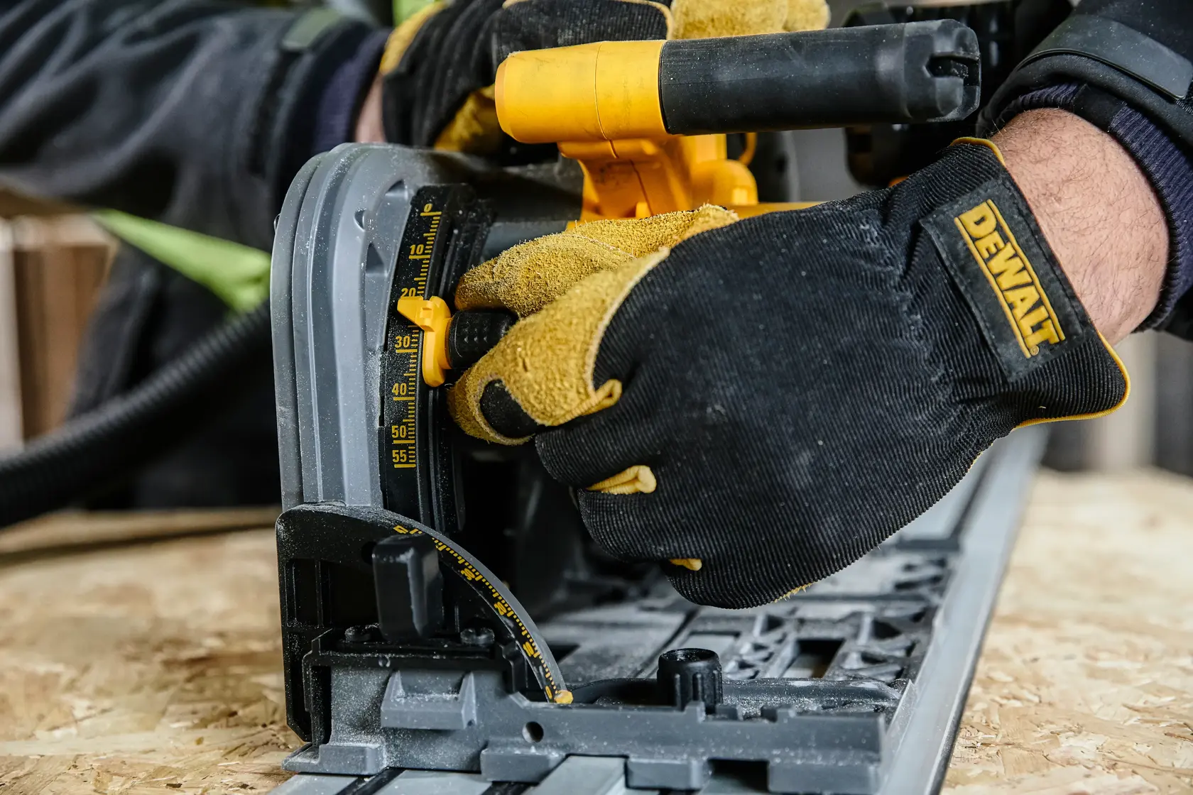 Gloved hands adjust a DEWALT circular saw angle on plywood. Close-up of tool and measurement gauge.