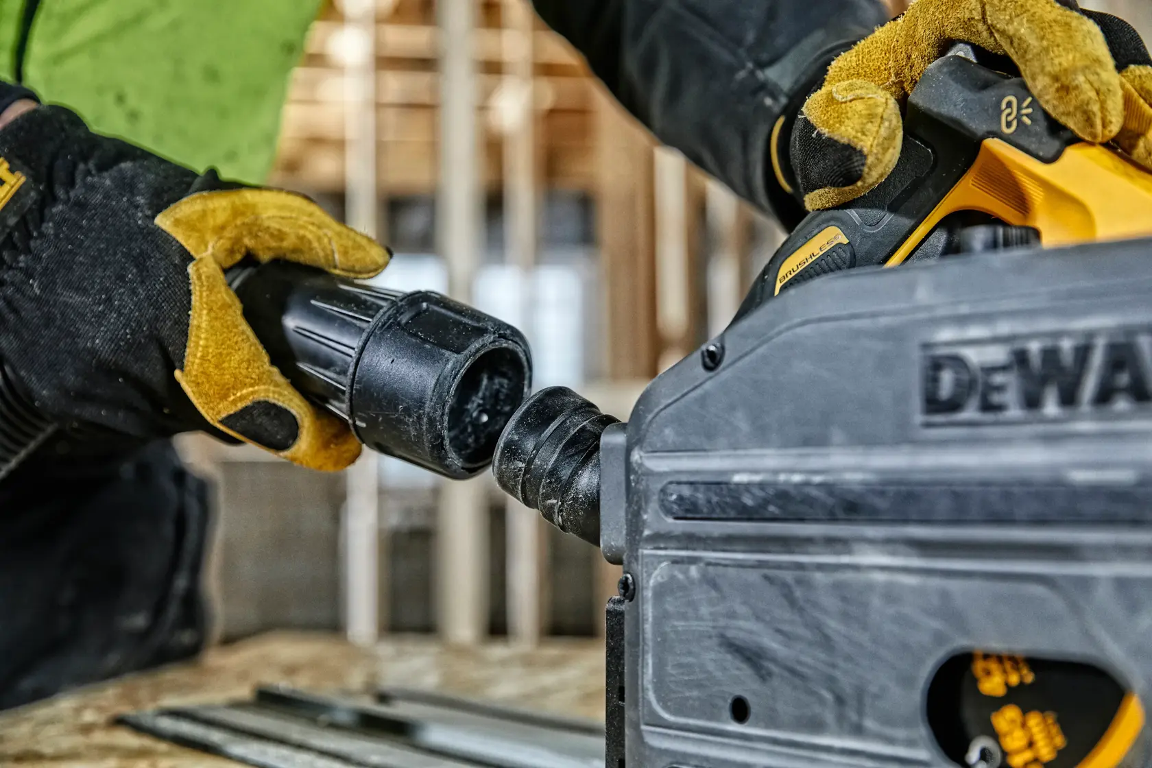 Gloved hands connecting a hose to a DEWALT power tool in a construction setting.