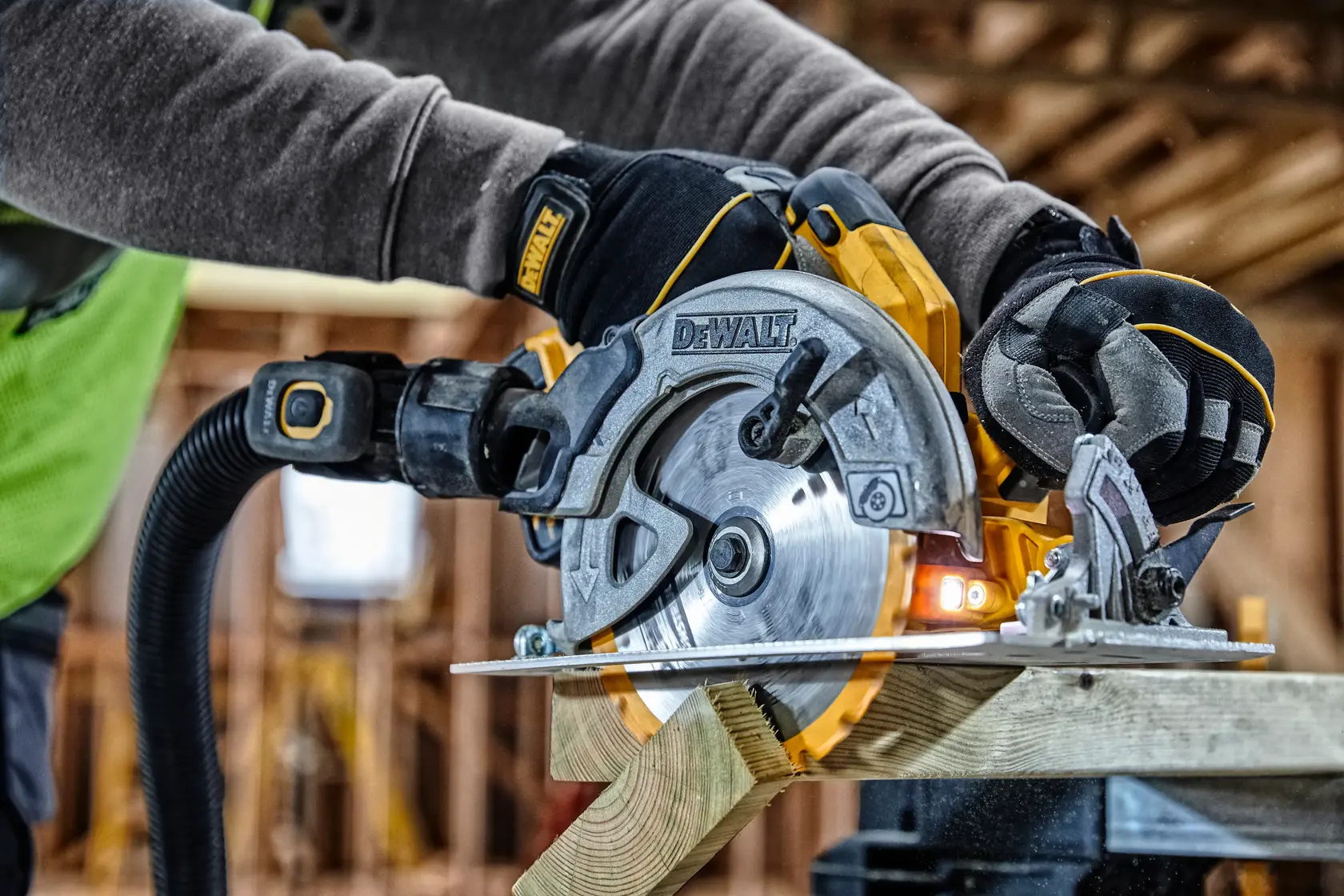 A DEWALT circular saw cutting wood, held by a gloved worker on a construction site.
