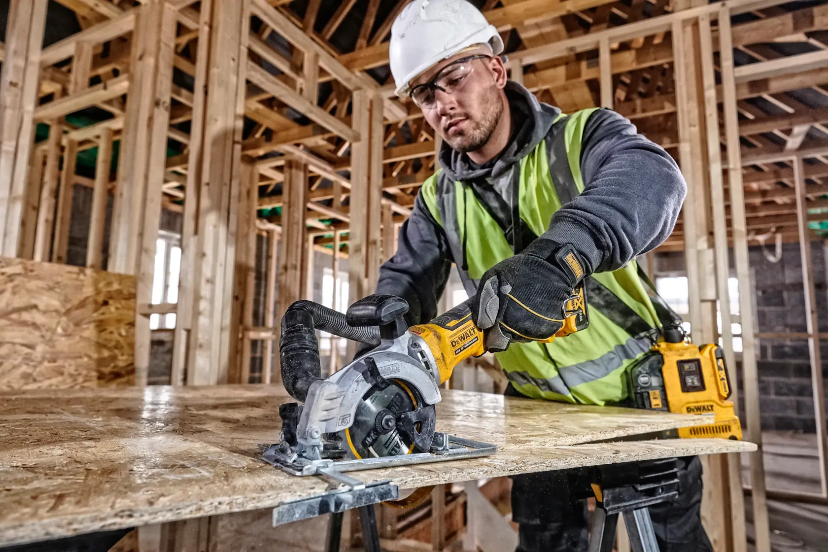 DEWALT DCS571NT-XJ, DCS571NT saw in use at construction site. Worker wears safety gear. Photography category.