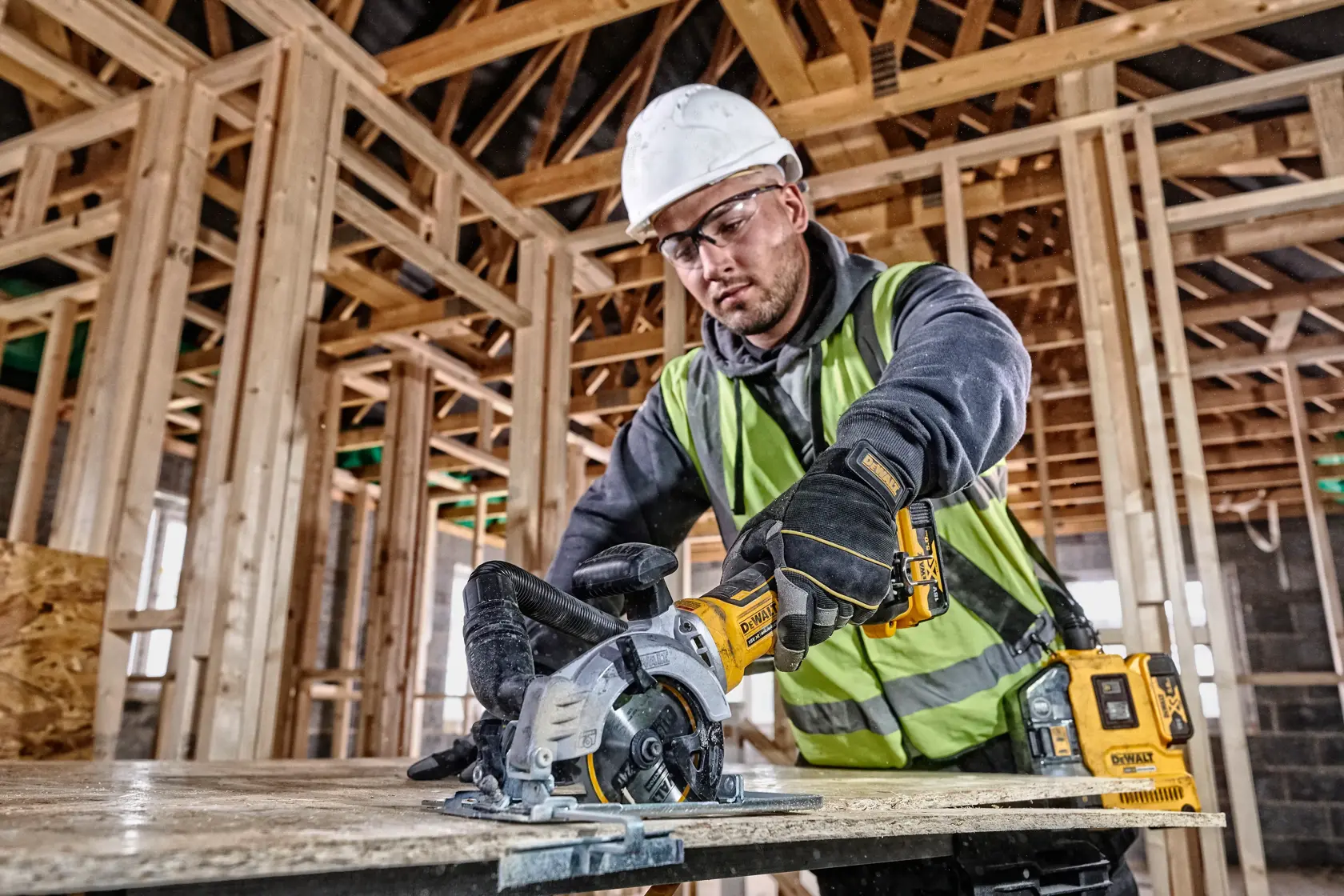 DEWALT DCS571NT-XJ and DCS571NT saw used by worker for wood cutting at construction site. Photography category.