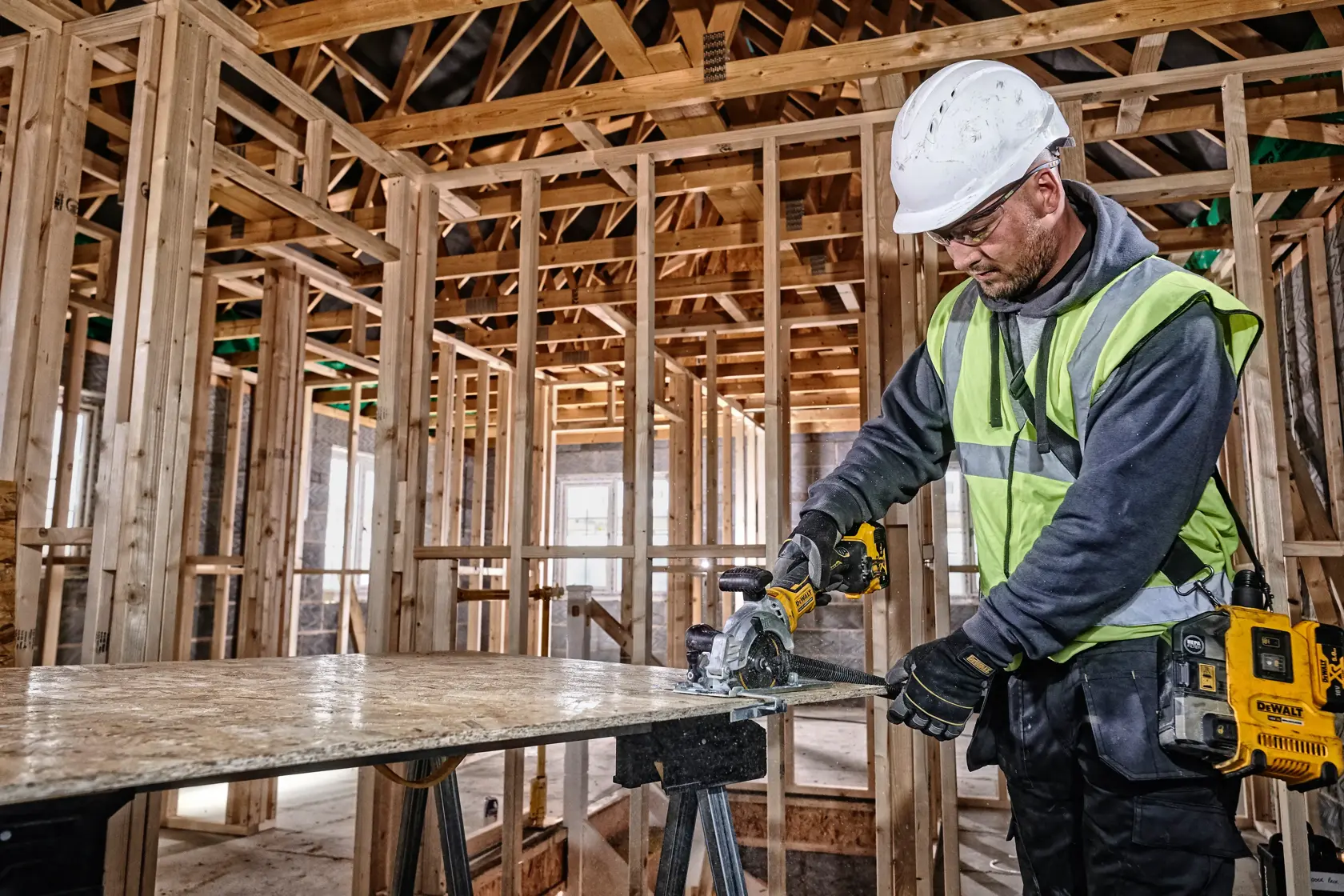 DEWALT DCS571NT-XJ, DCS571NT saw used on wood at construction site, worker in safety gear.