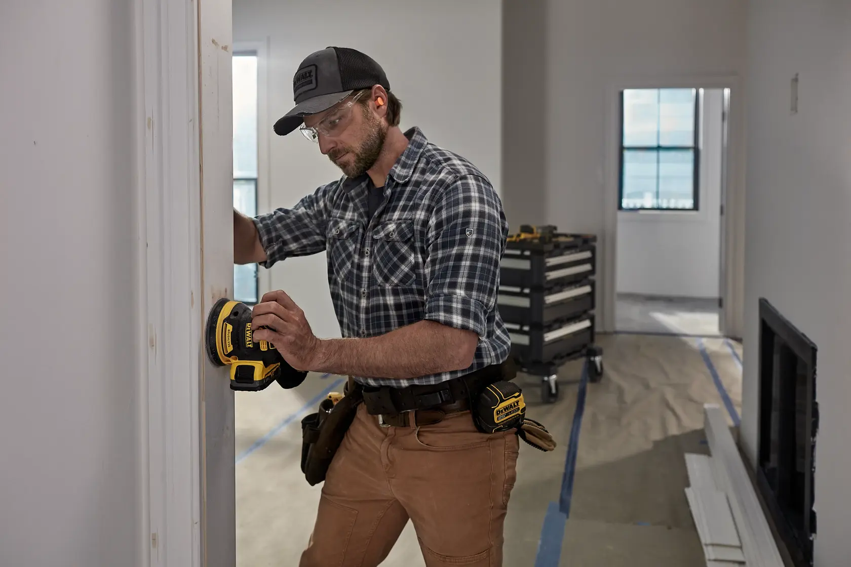 Person using DEWALT DCW210, DCW210D1 sander on door frame; tool belt visible; indoor workspace.