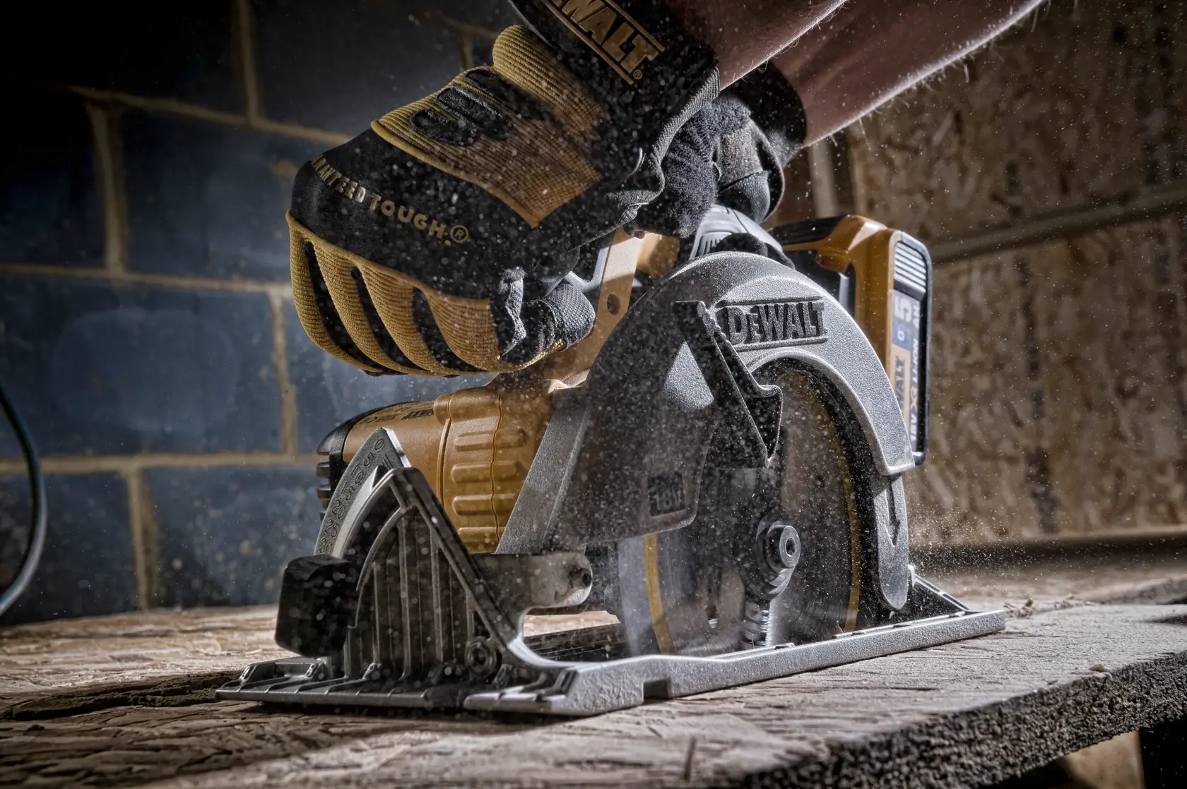 Gloved hand using a DEWALT circular saw to cut wood, with sawdust flying in a workshop setting.
