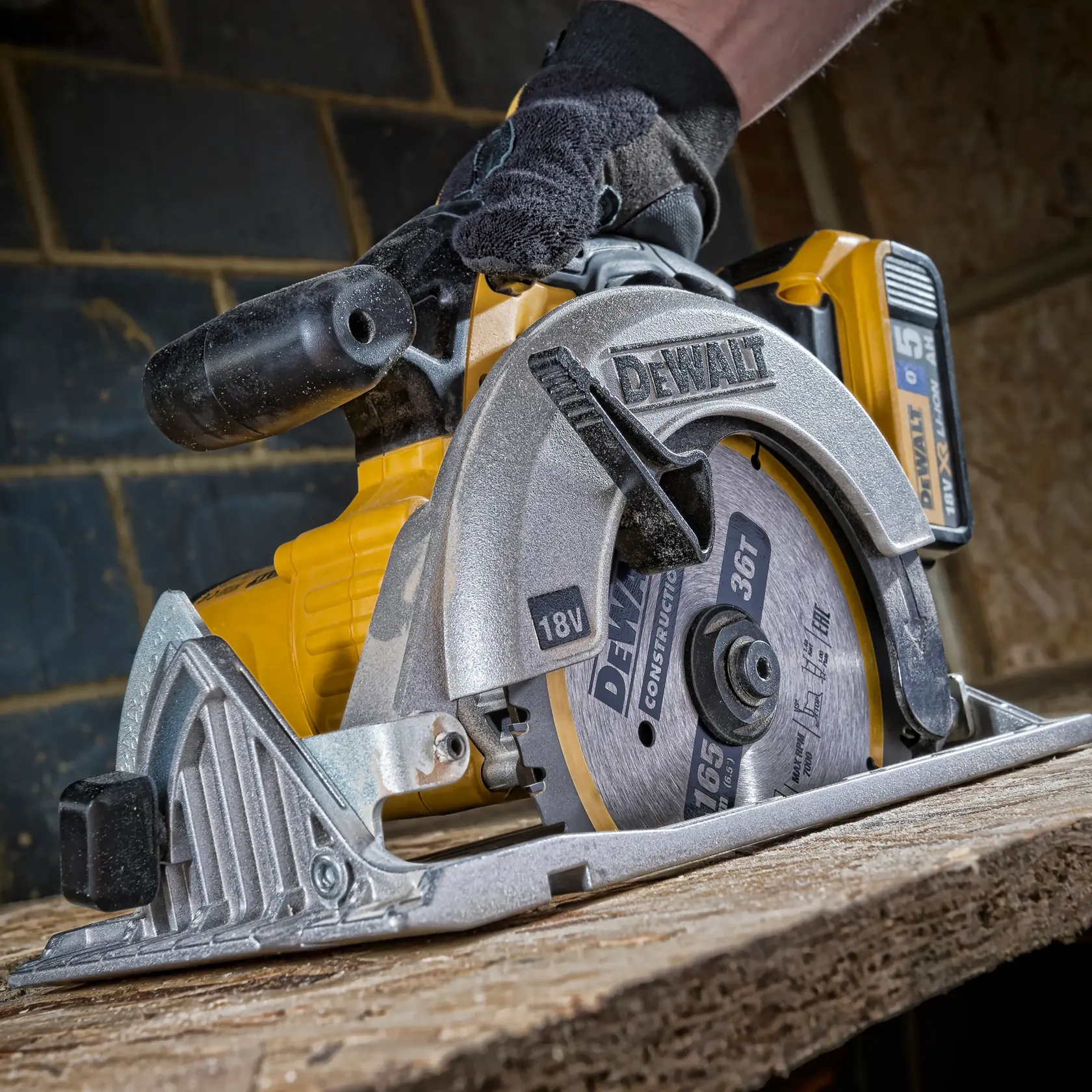 DEWALT DT1950 cordless circular saw cutting wood, close-up view with hand wearing glove.
