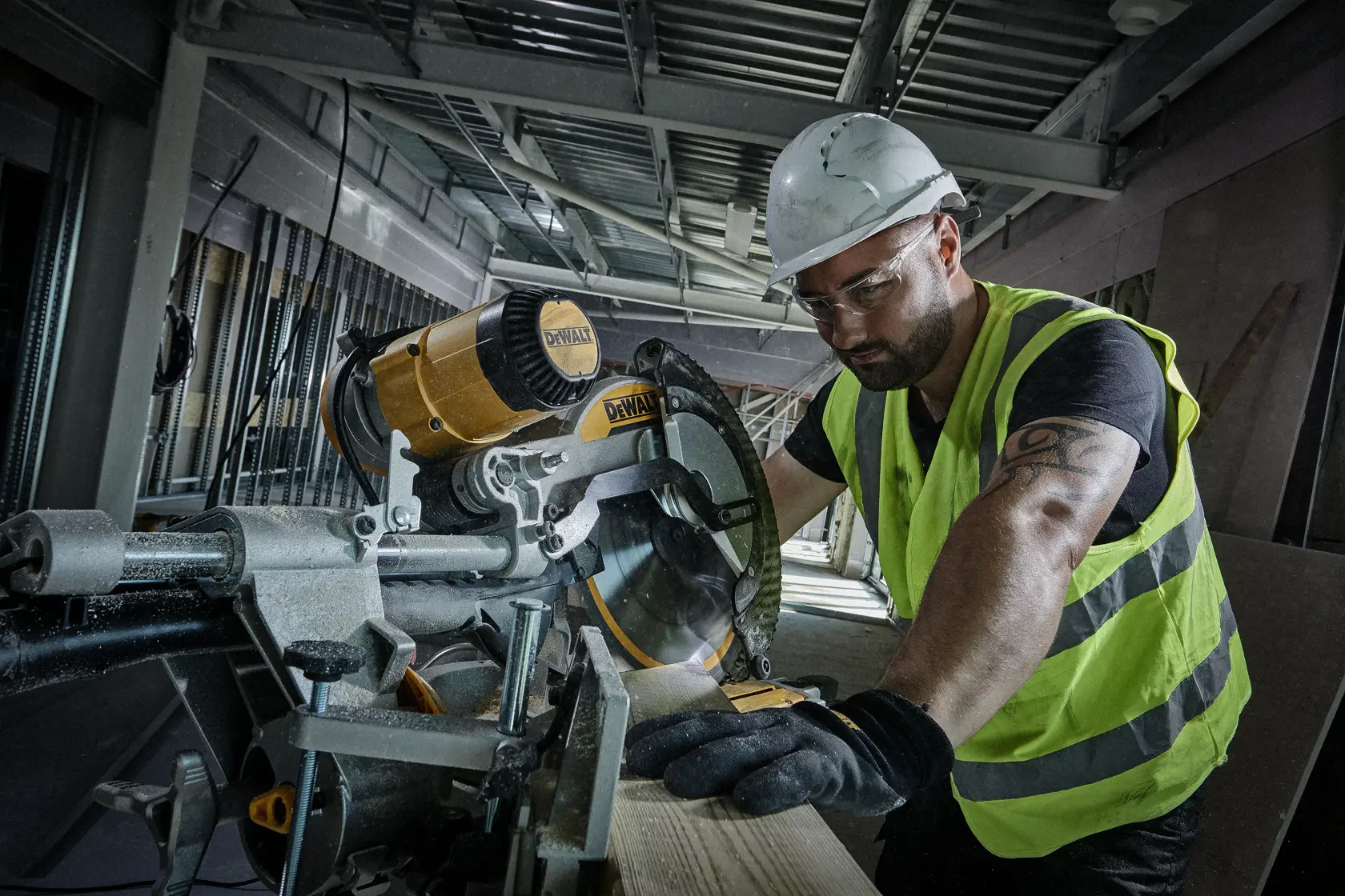 Worker using a DEWALT circular saw to cut wood at a construction site, wearing safety gear and high-visibility vest.