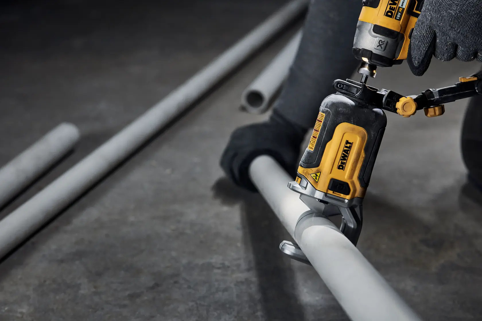 DEWALT tool cutting a metal pipe, operator uses gloves, indoor workspace, construction setting.
