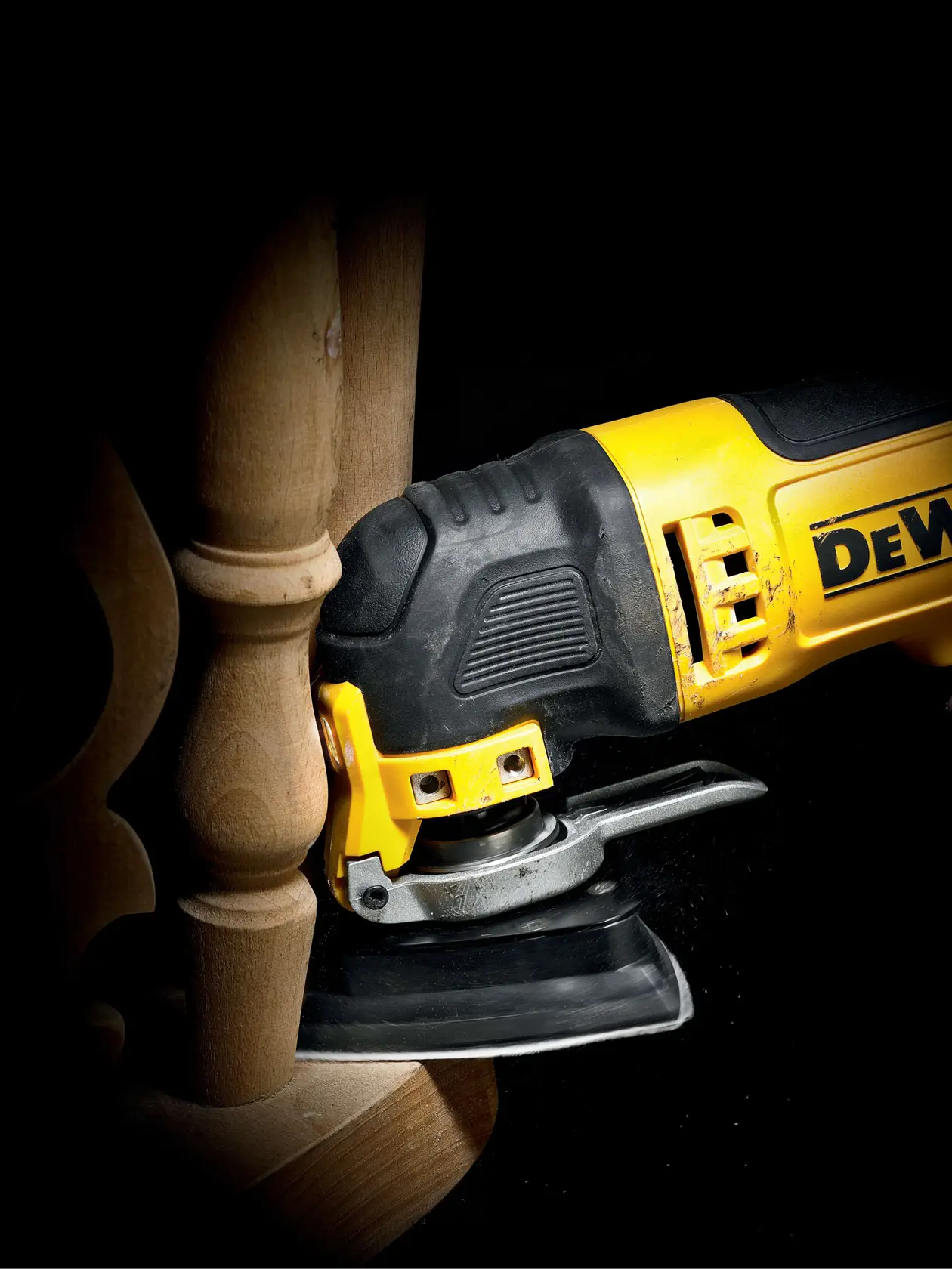 DEWALT multitool sanding wooden furniture in a close-up view, showing detail and precision work.