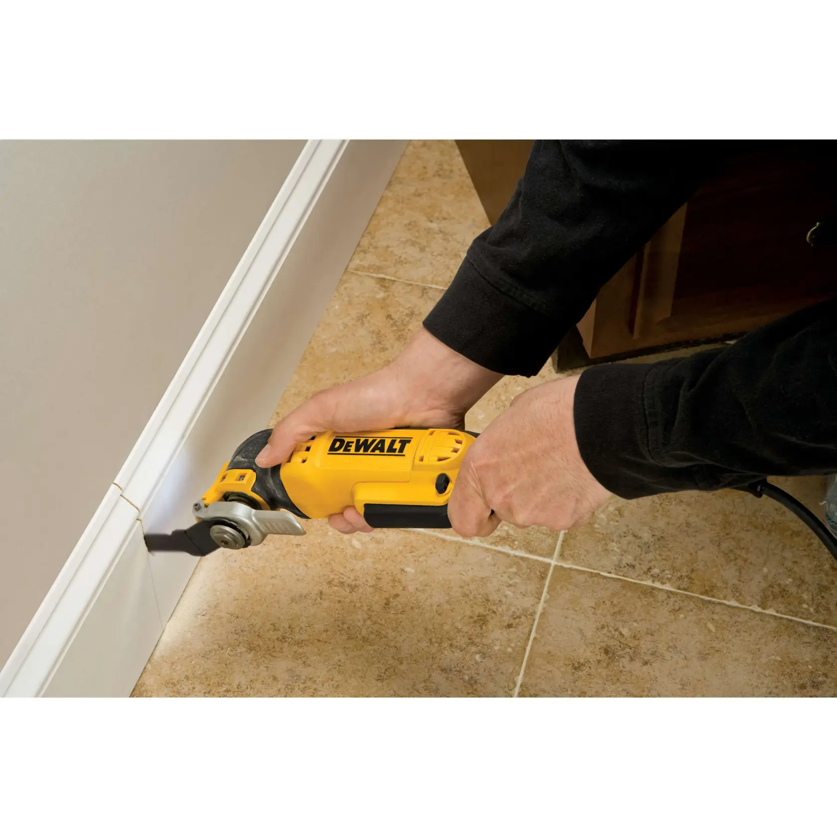 Person uses a DEWALT oscillating tool to cut along a baseboard on tiled floor.