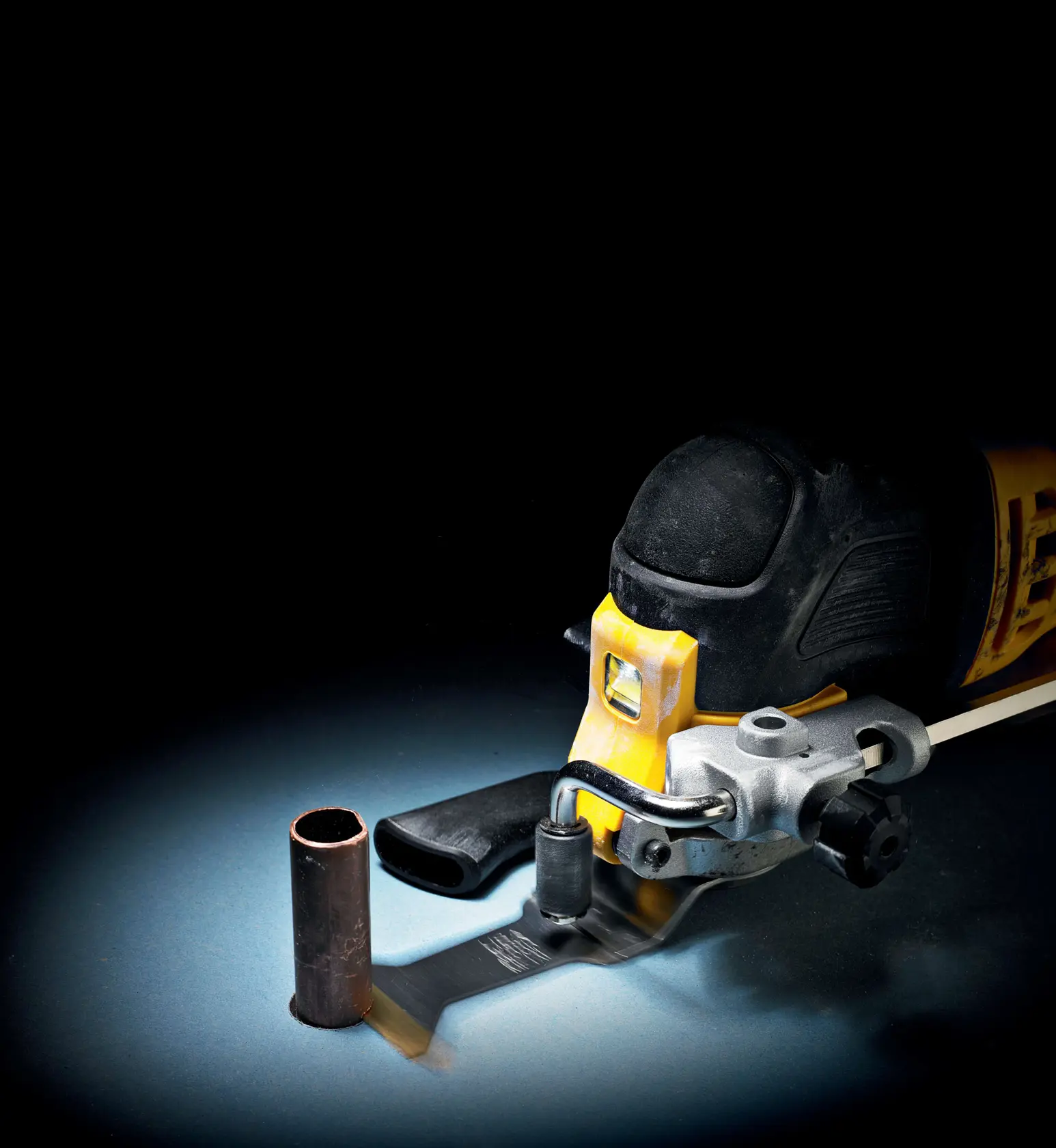 DEWALT tool with cutting blade slicing through a metal pipe on a dark background.