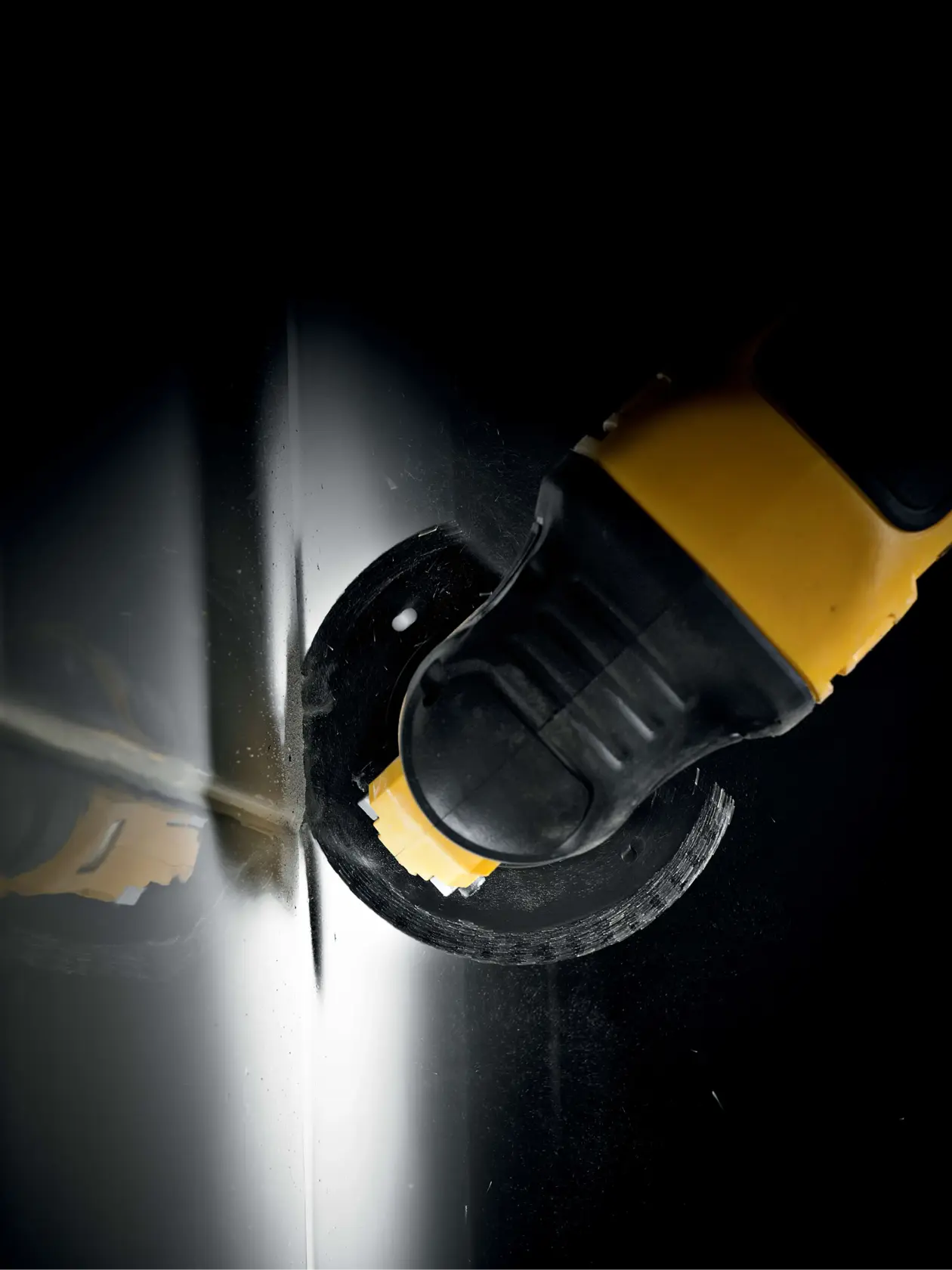 DEWALT tool with blade cutting through metal sheet, close-up view with dark background.