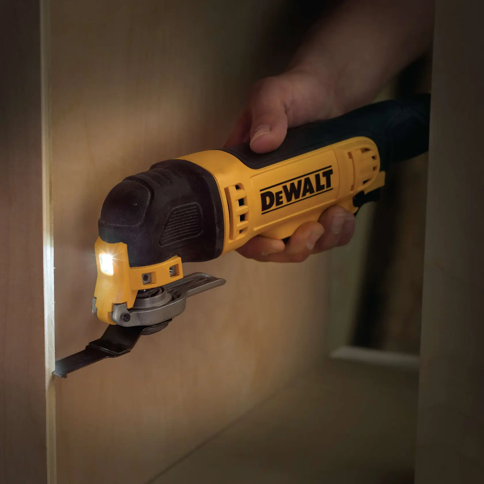 DEWALT multitool cutting wood with a blade, held by a hand. Tool has a yellow and black design with LED light.