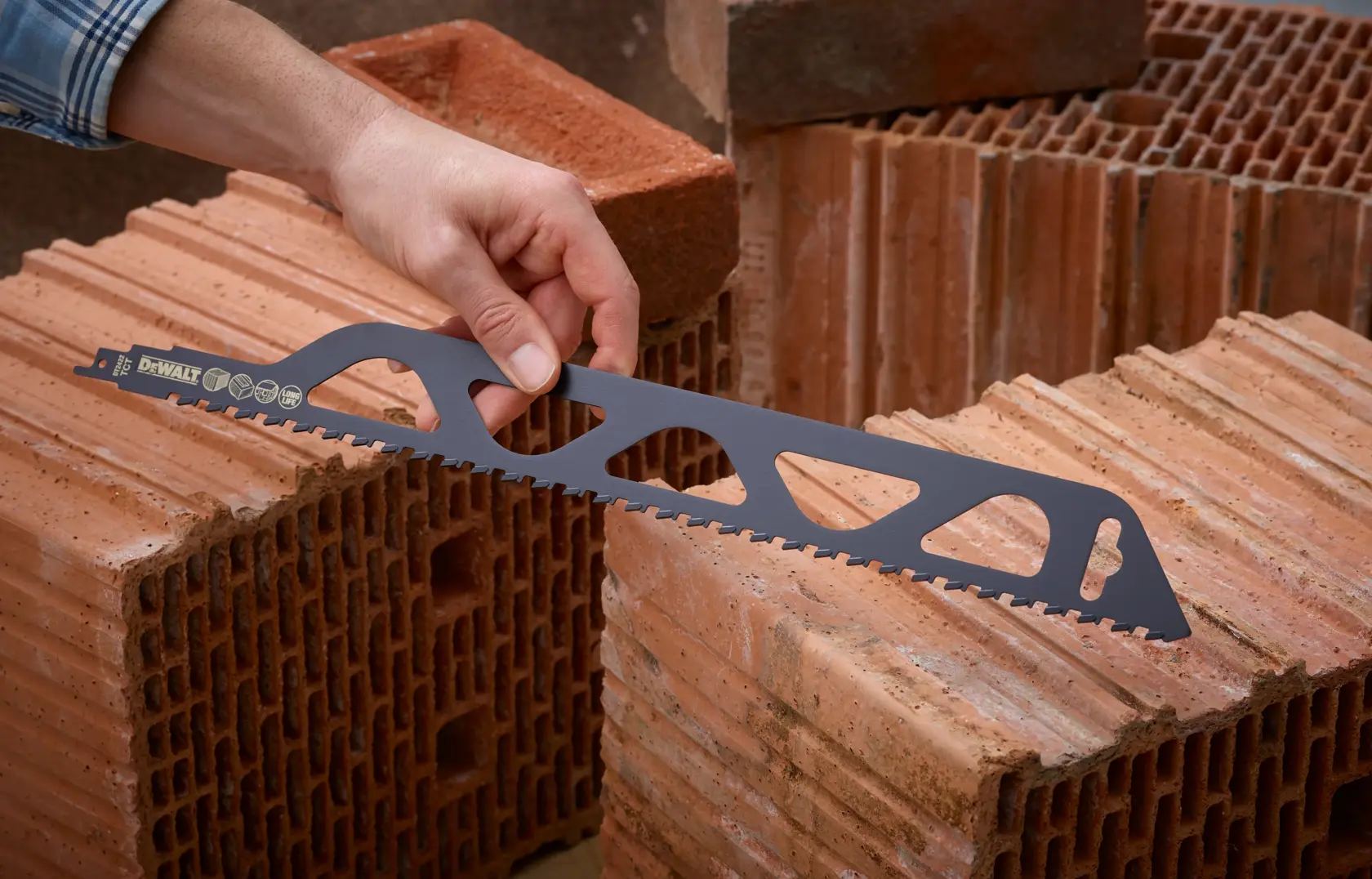 Person holding DEWALT saw blade for bricks, positioned on hollow clay blocks in a construction setting.
