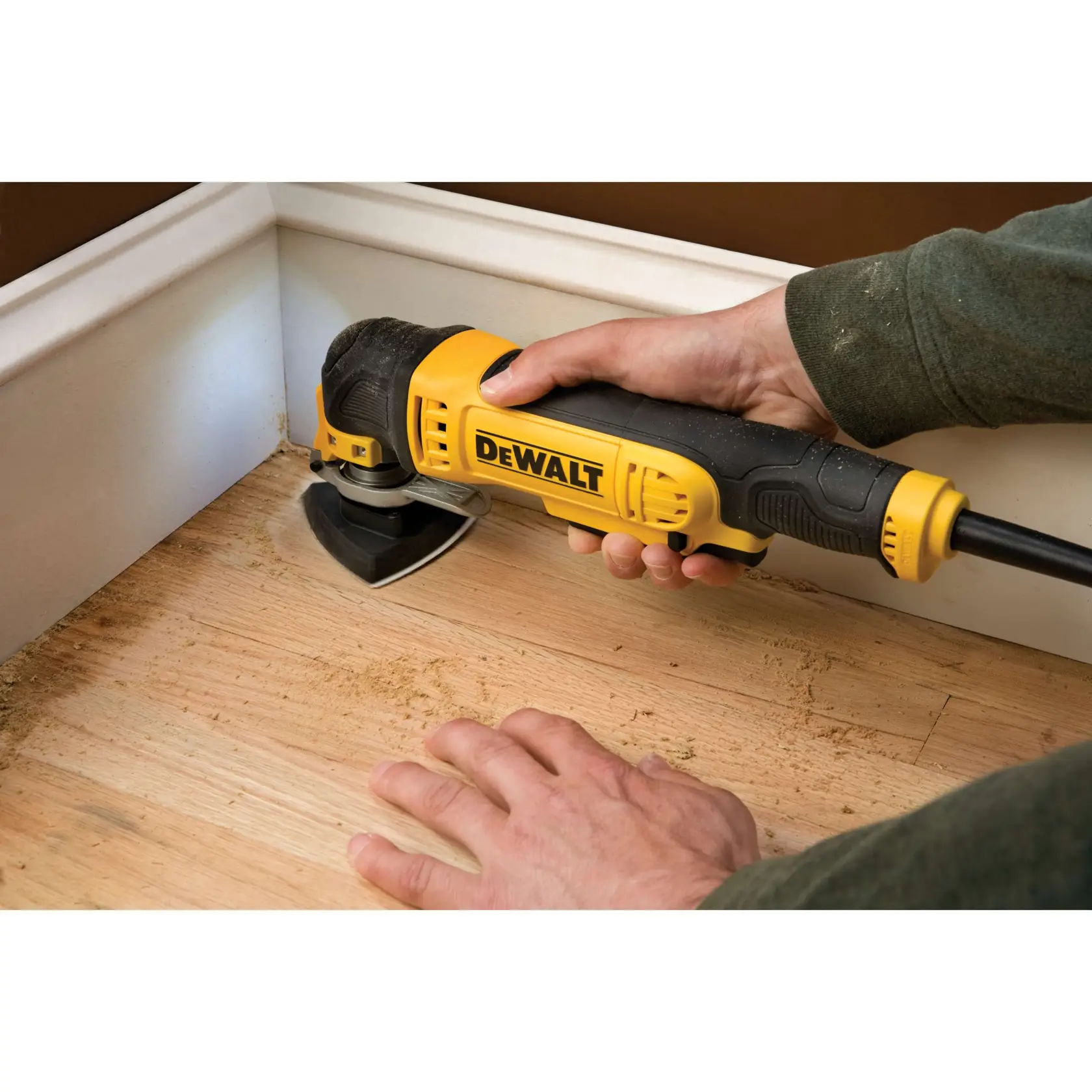 A DEWALT power tool is used to sand a wooden floor near a corner, held by a person.