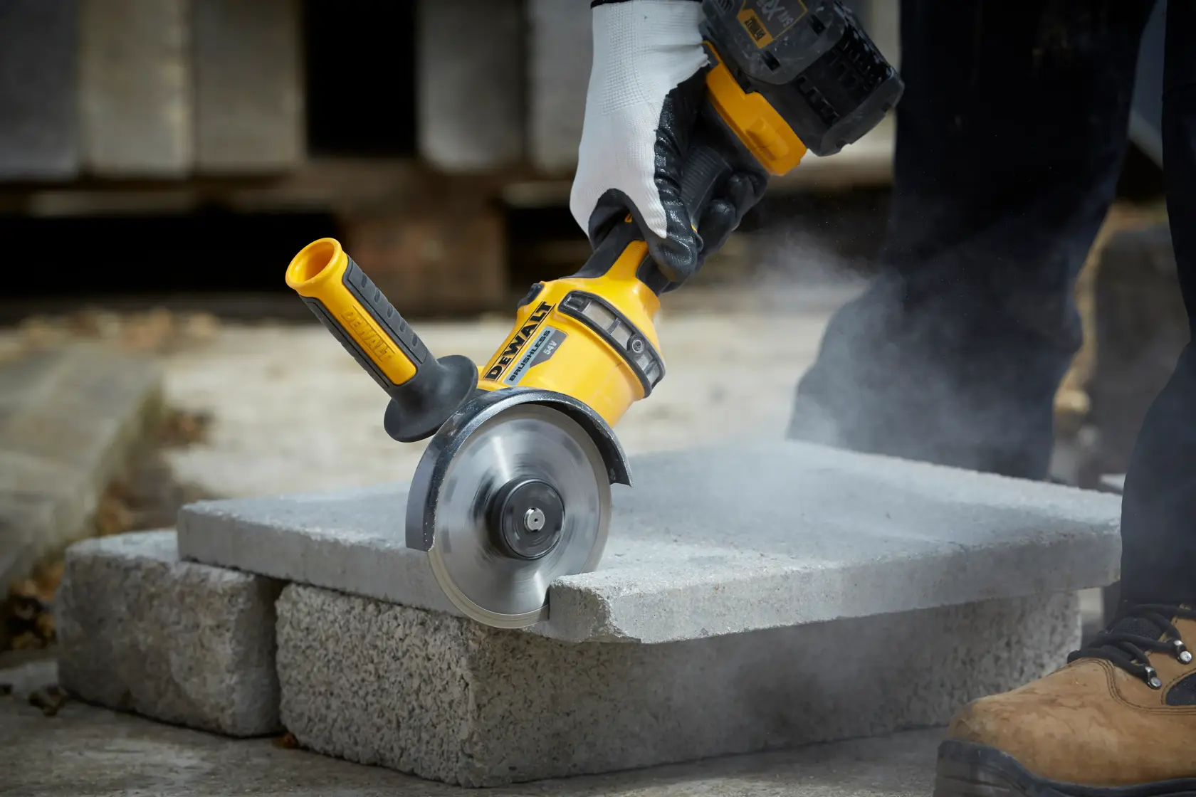 DEWALT DT3712 tool cutting concrete block outdoors, with dust and worker's gloved hand visible.