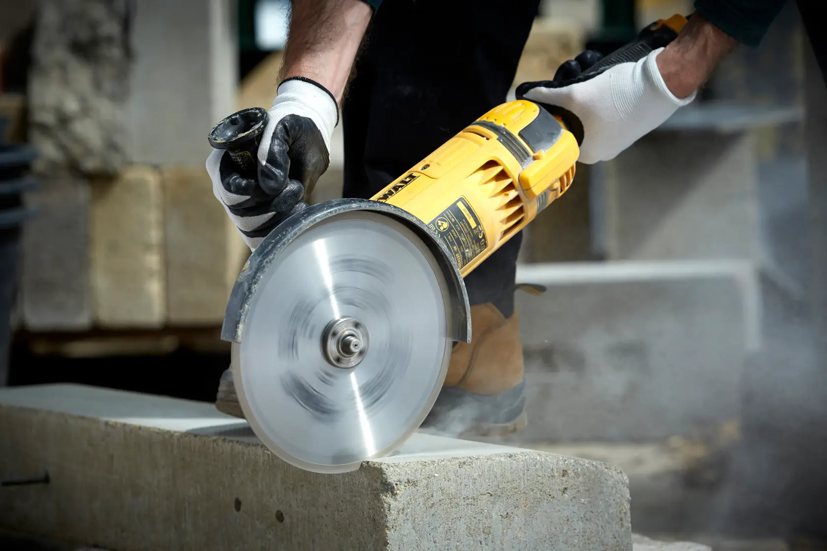 DEWALT DT3731 cutting disc in use, slicing concrete block, operator wearing gloves for safety.
