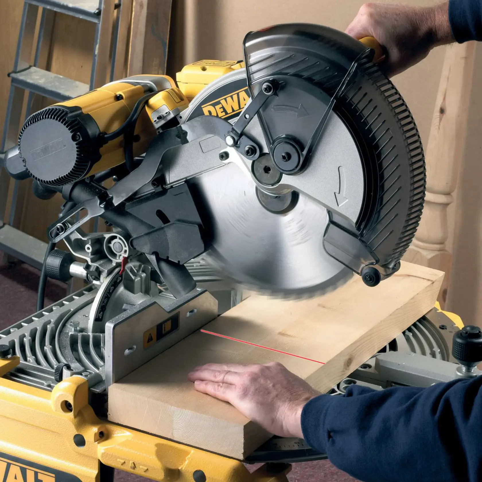 Person using a DEWALT miter saw to cut a wooden plank, with a laser guide on the work surface.
