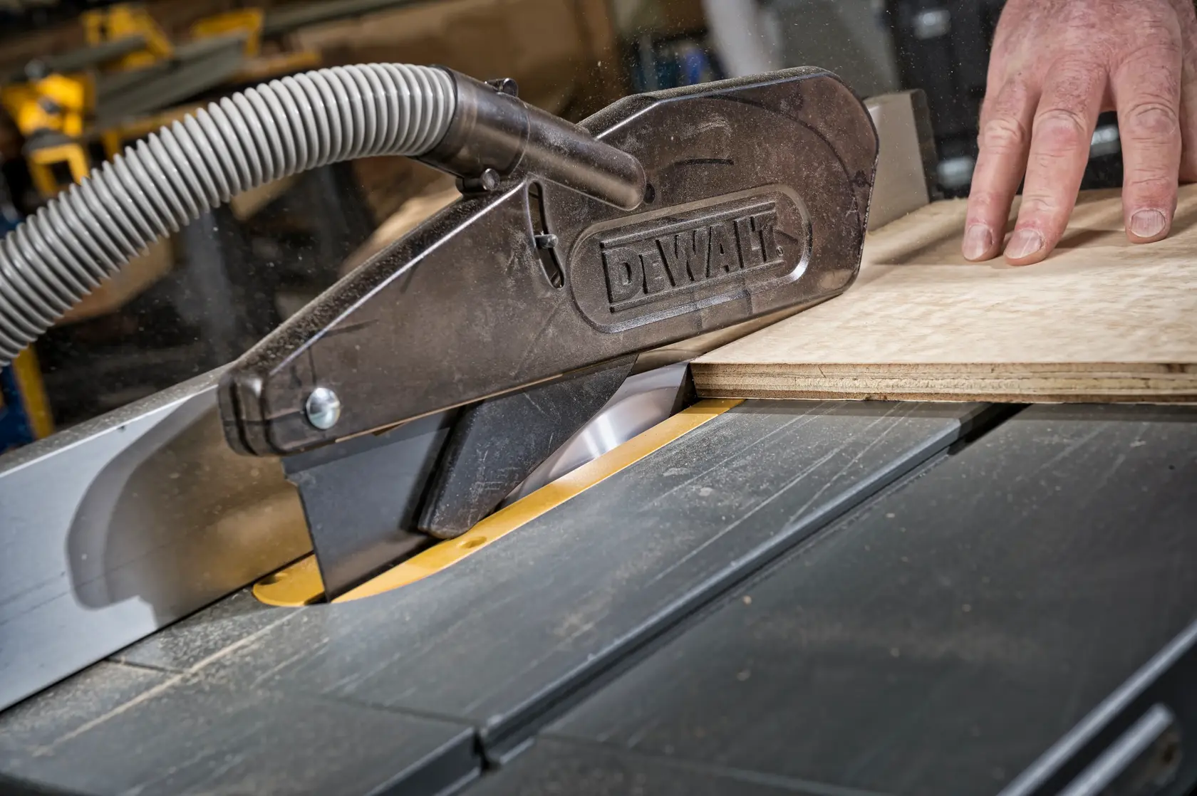 DEWALT DT4226 table saw with dust extraction cutting wood in a workshop.