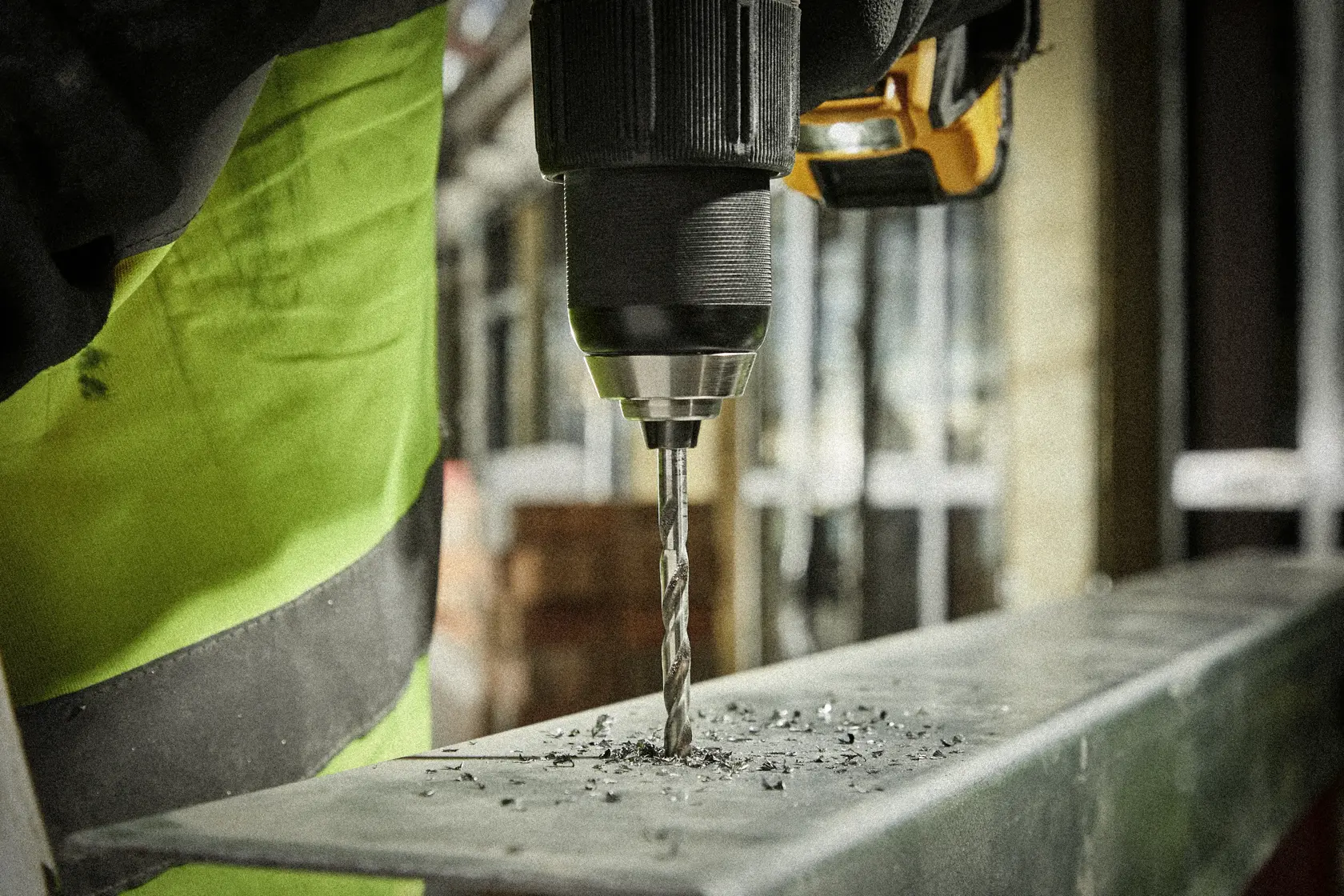 Close-up of a drill making a hole in a metal surface, with metal shavings around the bit.