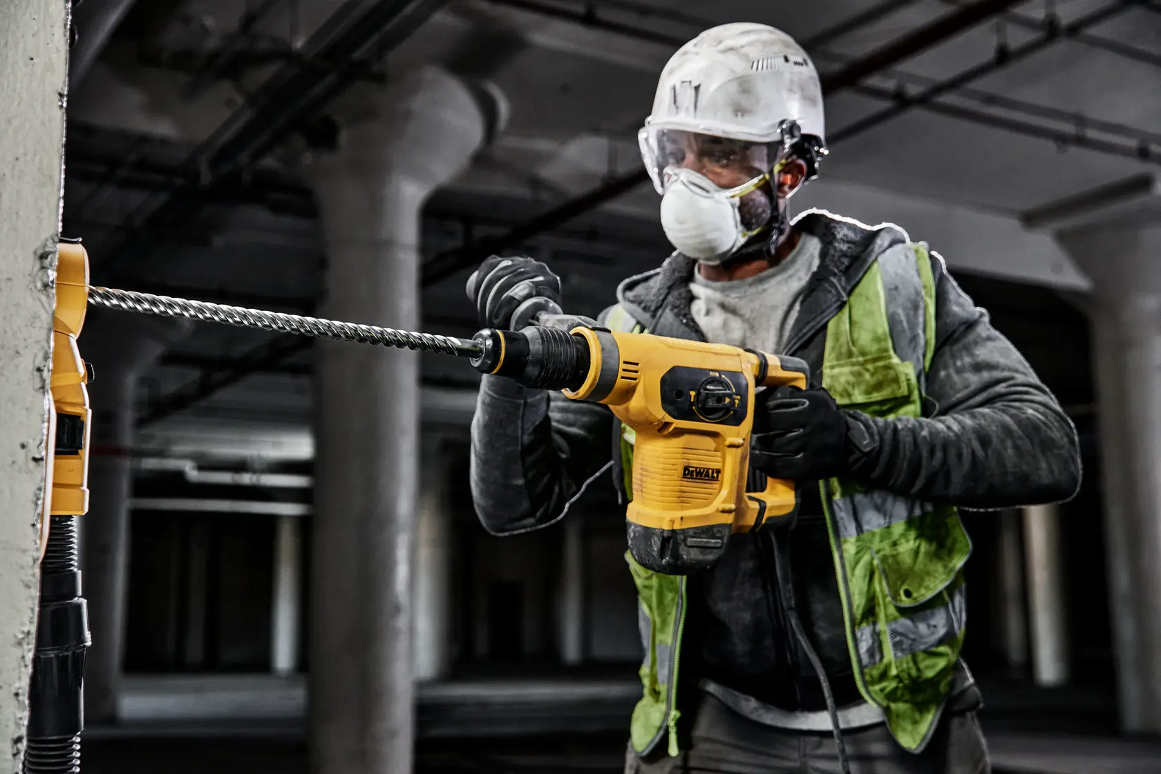 Worker uses DEWALT rotary hammer drill with DT60828 bit on concrete at a construction site.