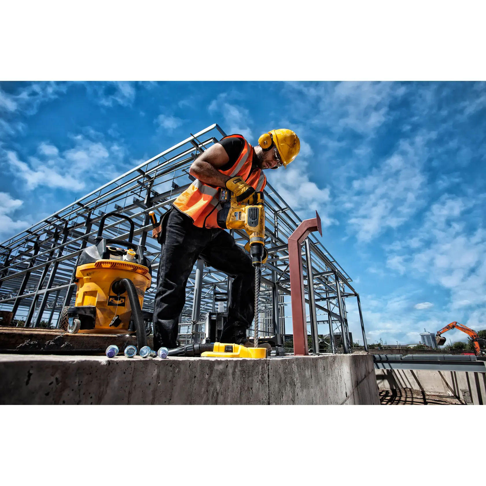 Worker using DEWALT power tool at a construction site with steel beams and blue sky in the background.