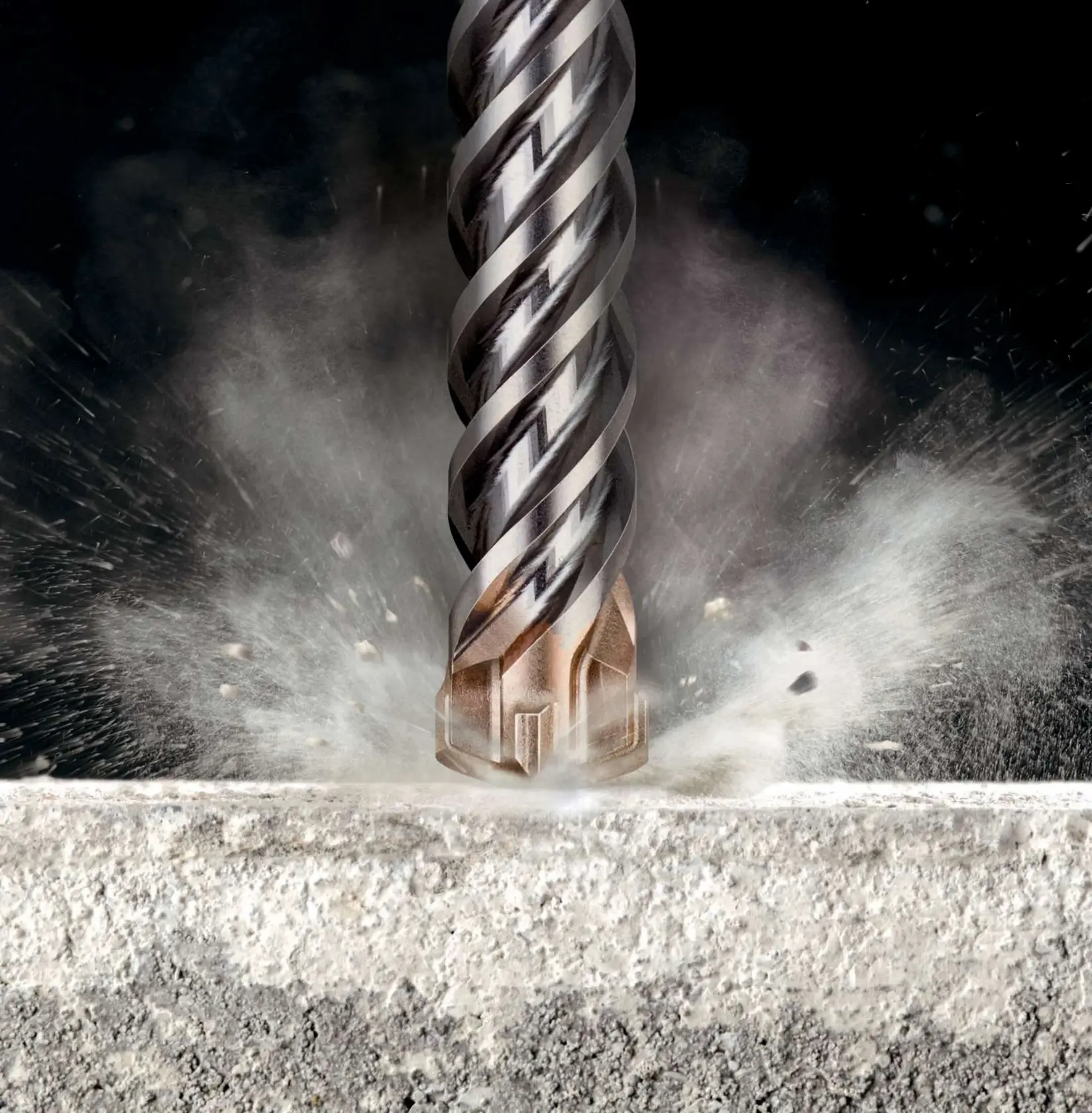 Close-up of a DEWALT masonry drill bit breaking through concrete with dust and debris flying.
