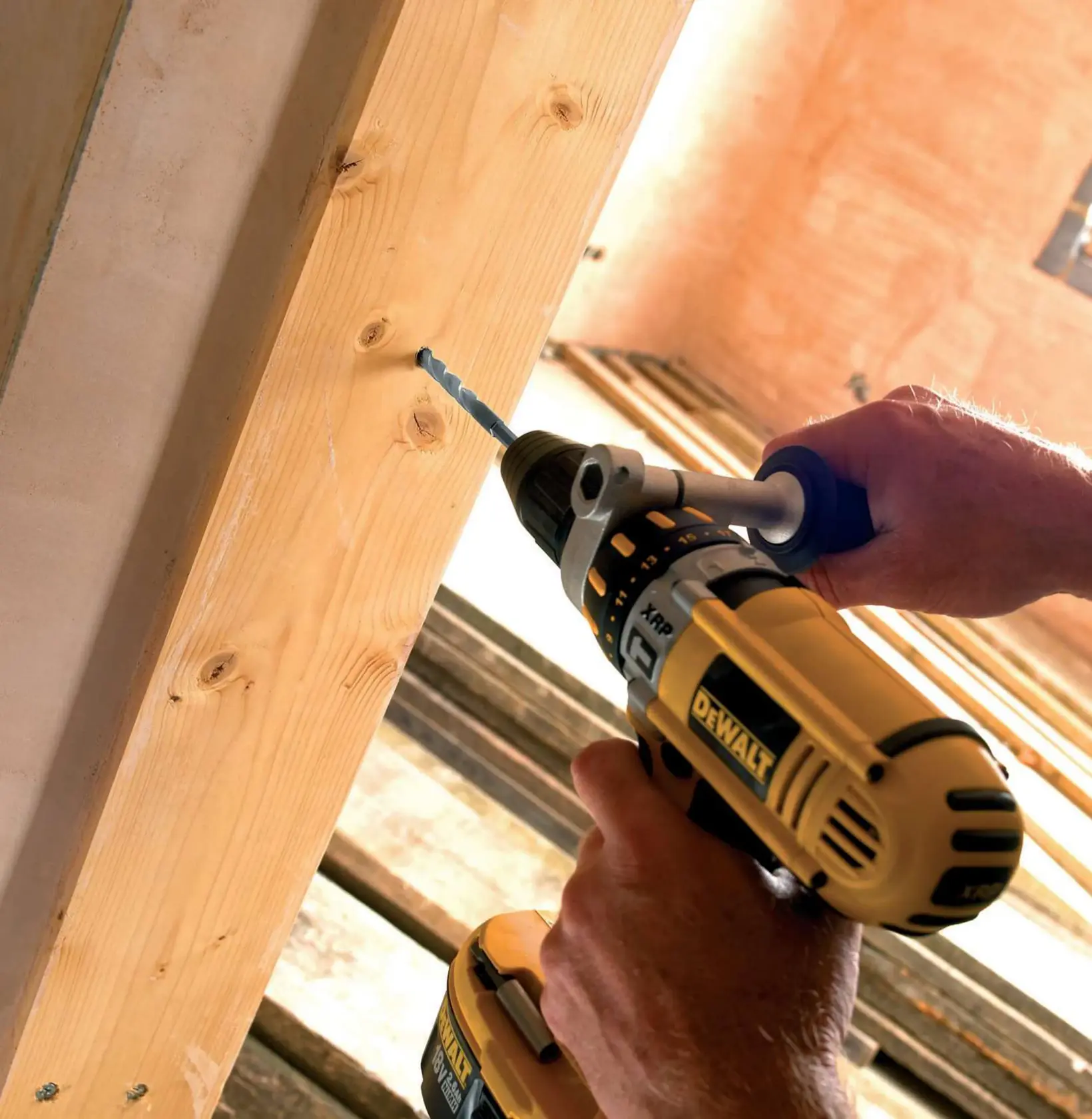 A DEWALT cordless drill is used to drill a hole in a wooden beam during construction work.
