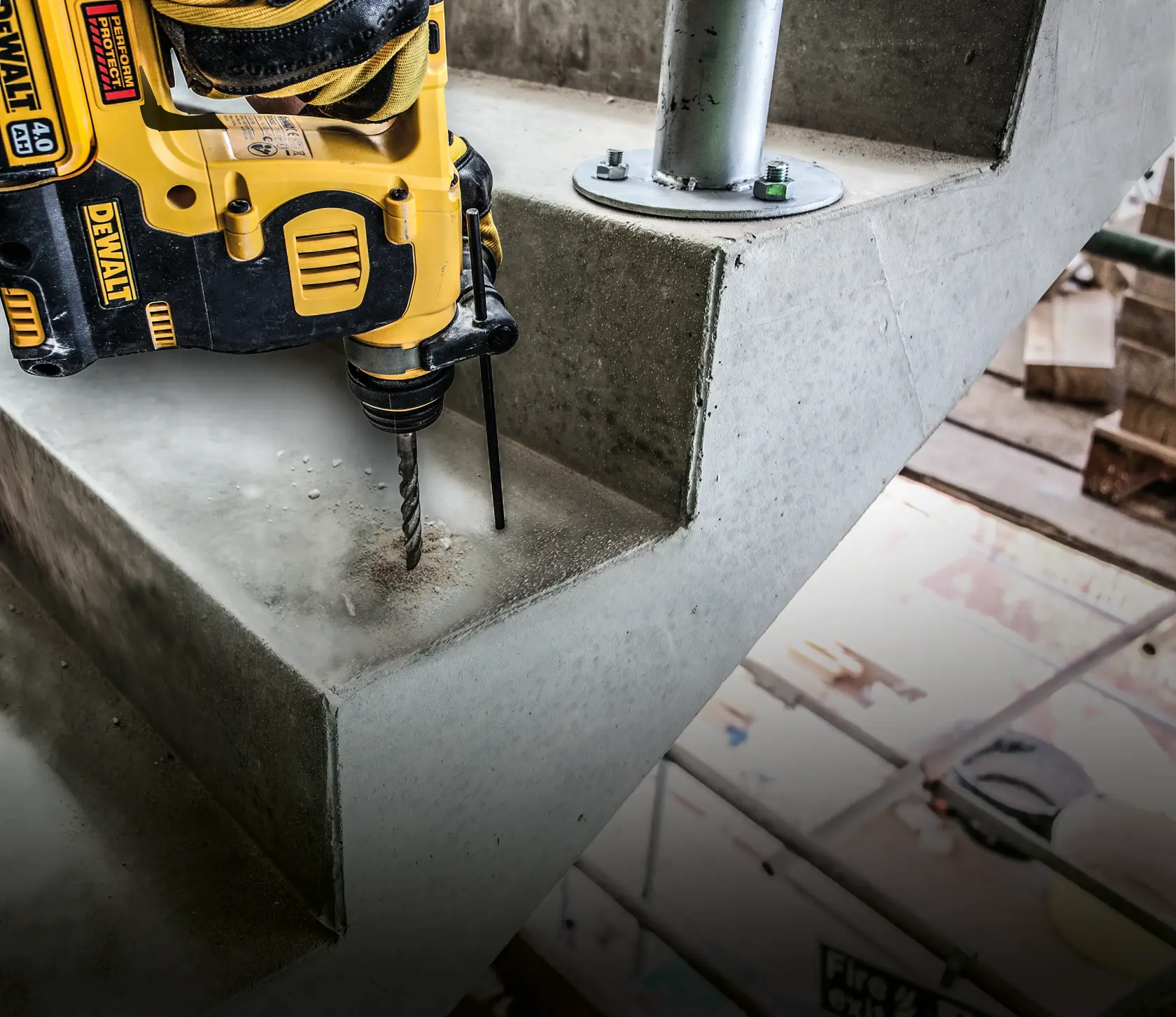 DEWALT drill in use on a concrete staircase, creating a hole near a metal post at an indoor construction site.