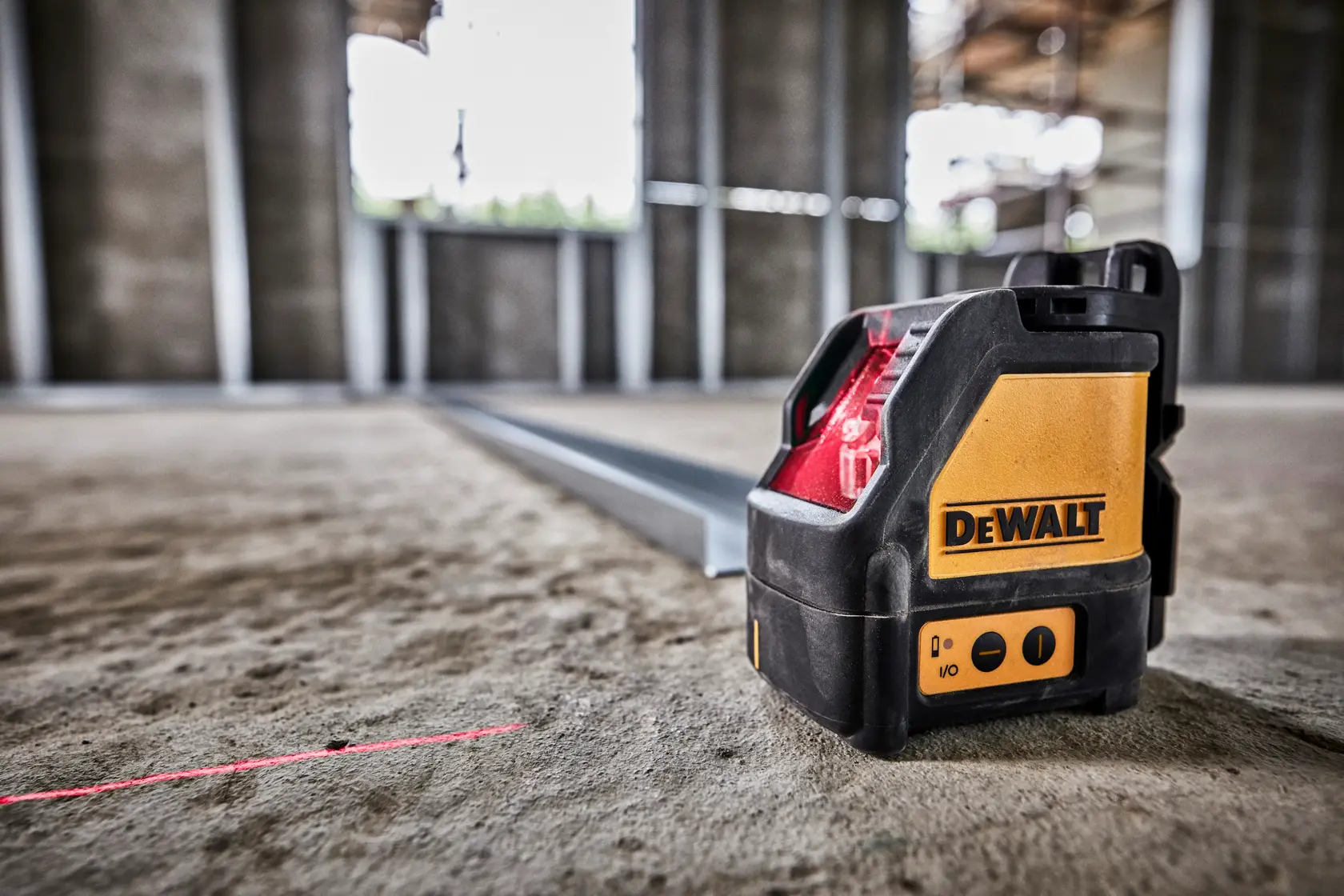 DEWALT laser level emits a red line on a construction site floor for accurate measurements.