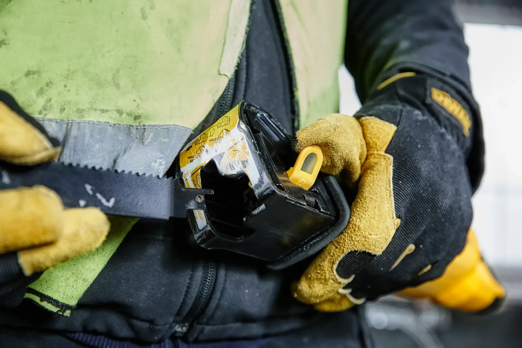 Gloved hands attach a DEWALT tool to a belt, showing close-up of work gear and rugged gloves.