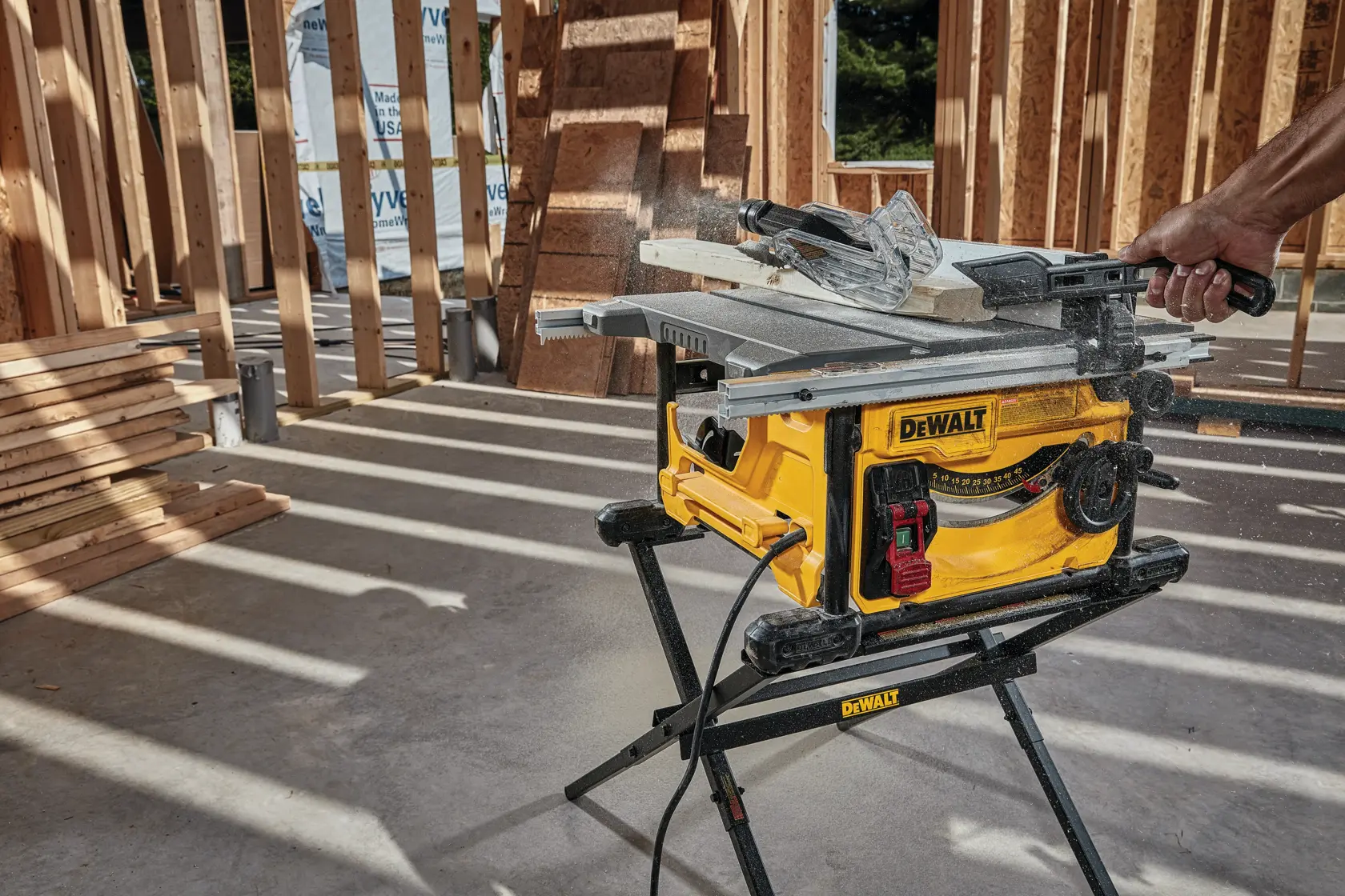 DEWALT DWE7485WS and DWE7485 saw used outdoors at construction site. Worker cuts wood. Scaffolding in background.